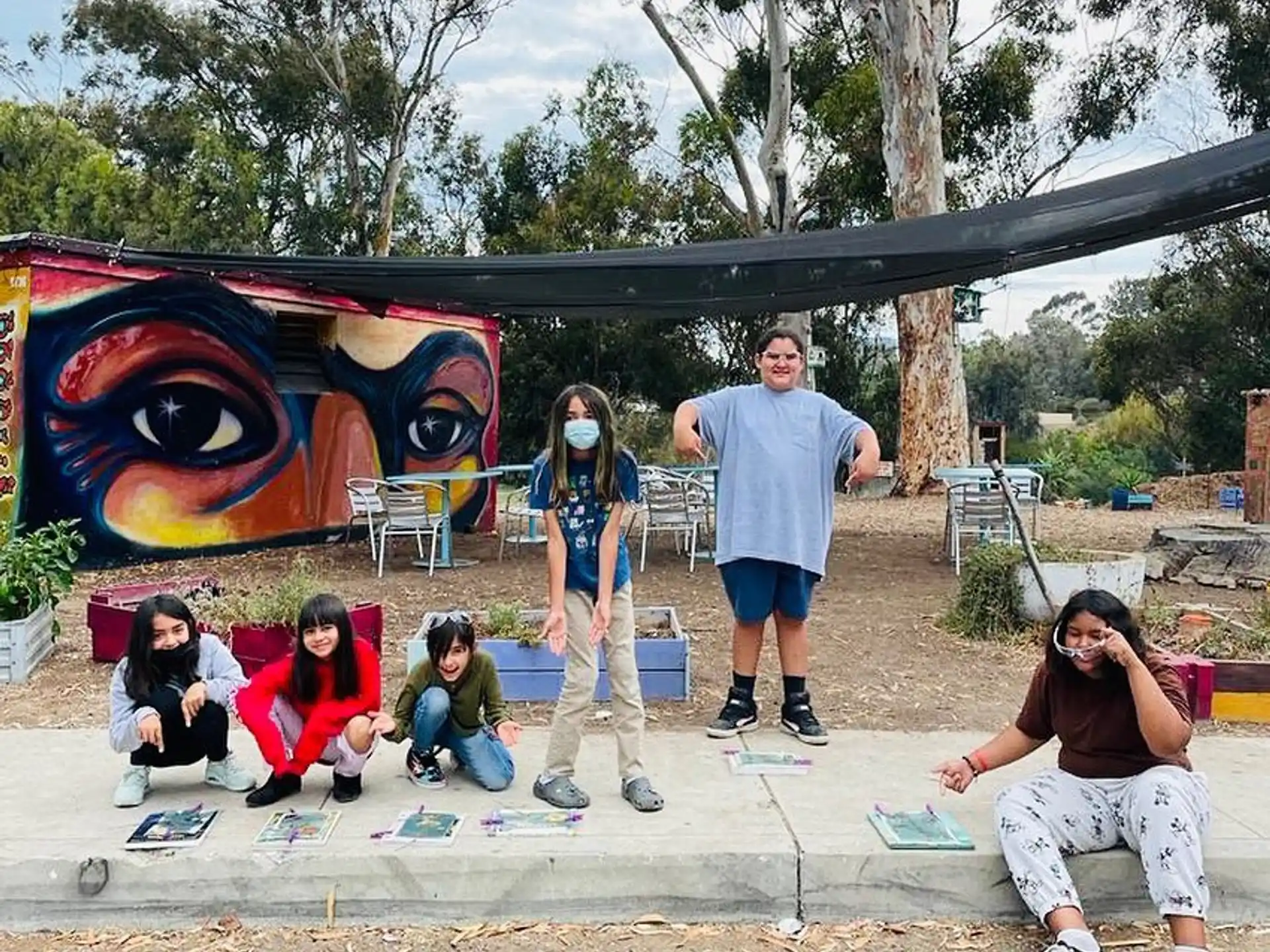 a group of people sitting on the ground next to a wall with graffiti