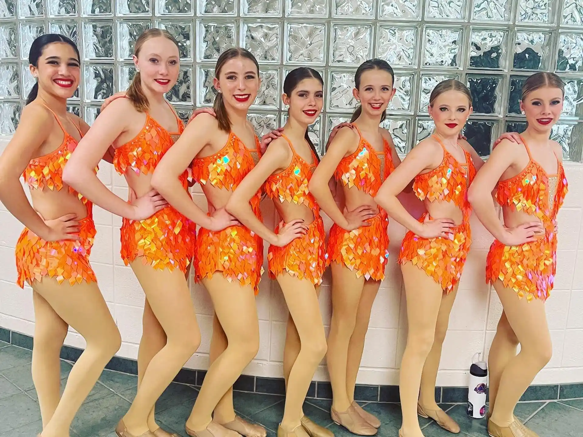 a group of women in orange dresses