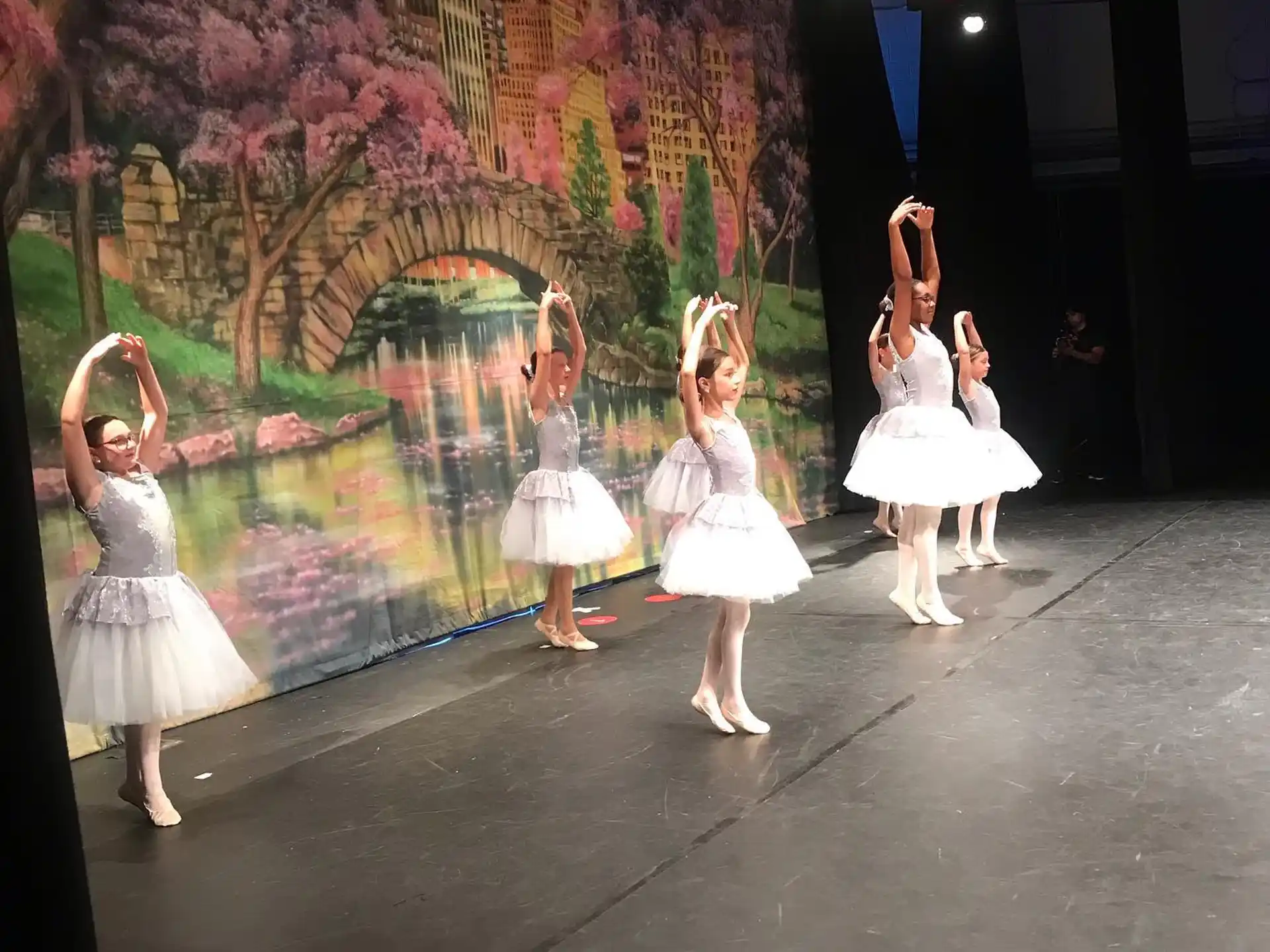 a group of girls in white dresses dancing on a stage