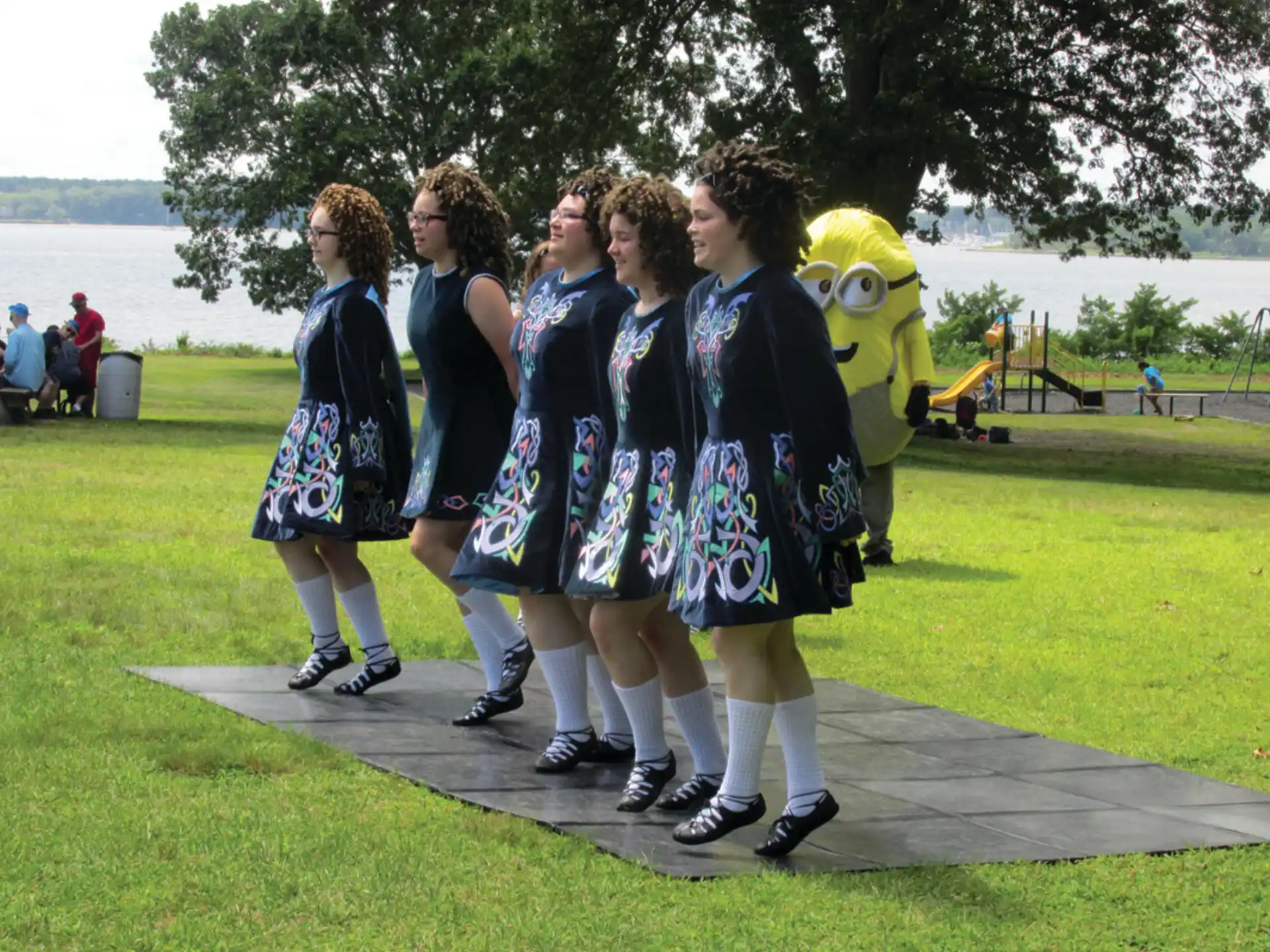 a group of women in black and white dresses standing on a stone path