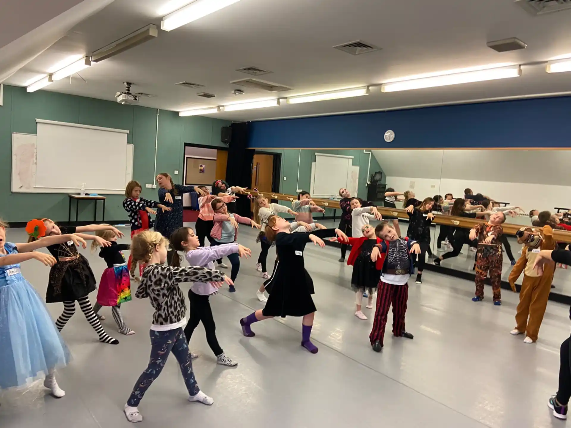 a group of children dancing in a room with a whiteboard