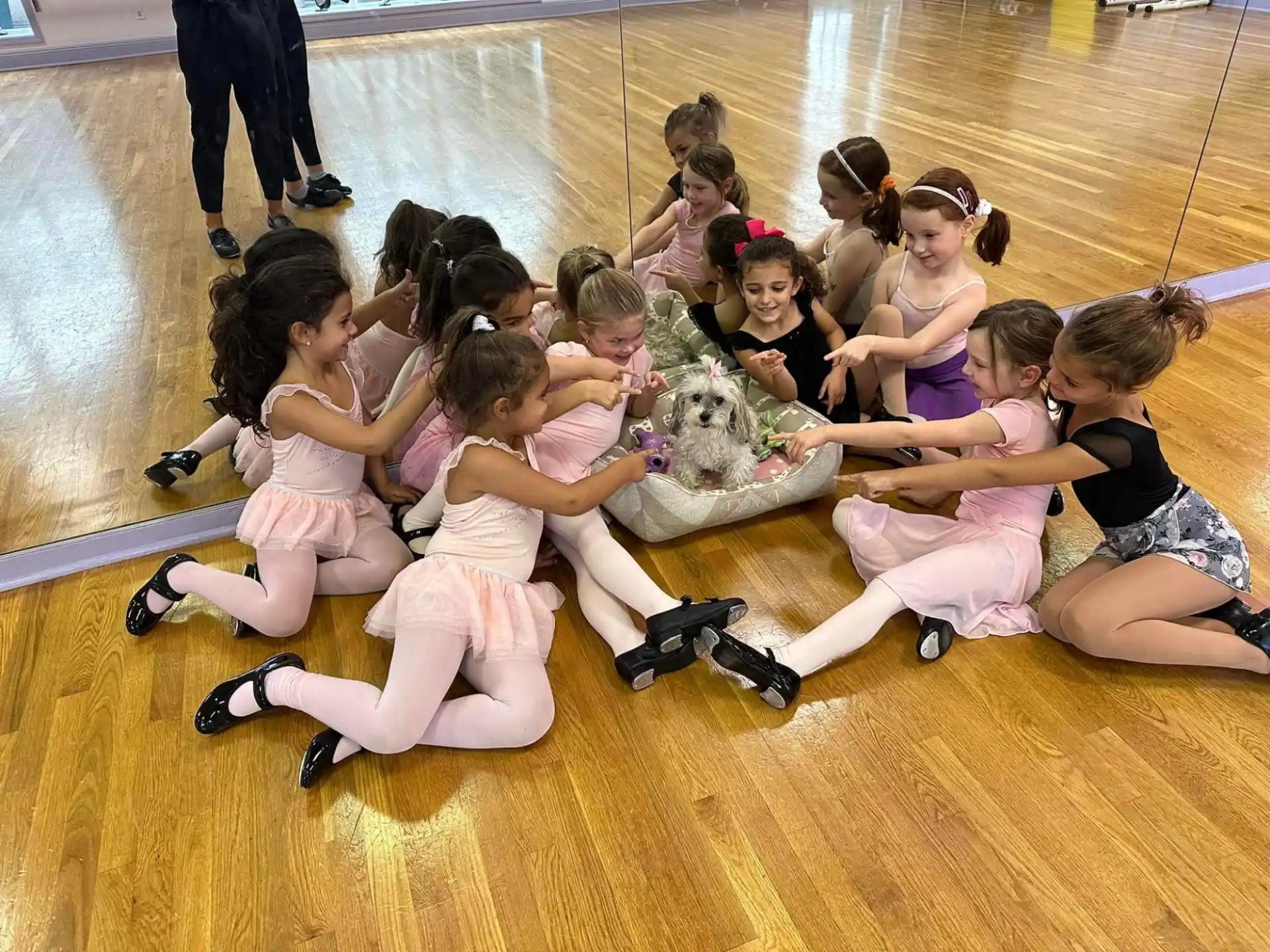a group of girls kneeling on the floor and holding a stuffed animal