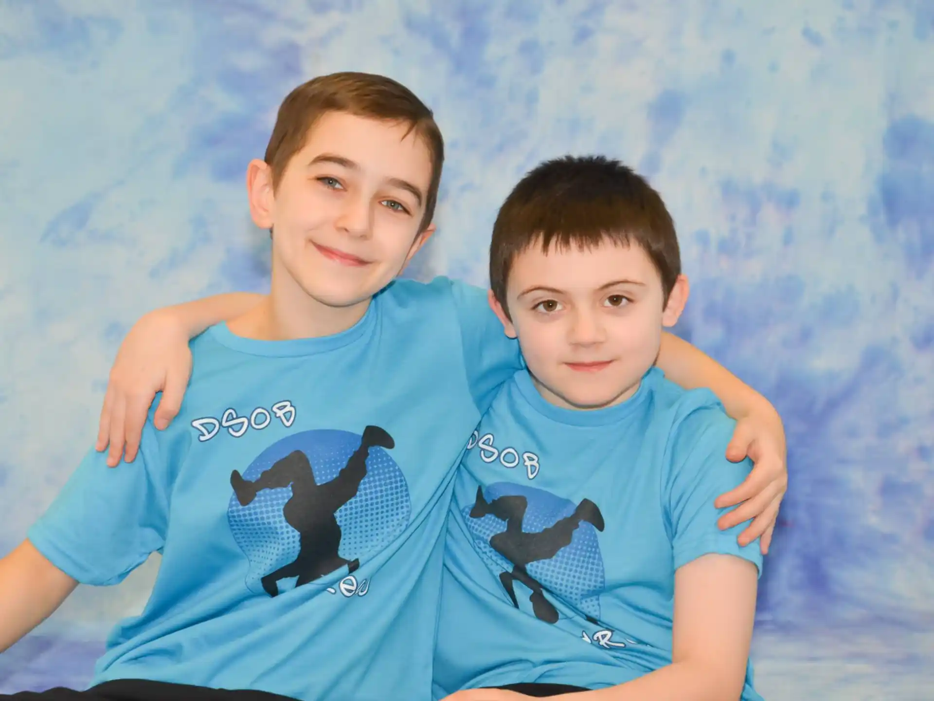 two boys lying on a blue blanket