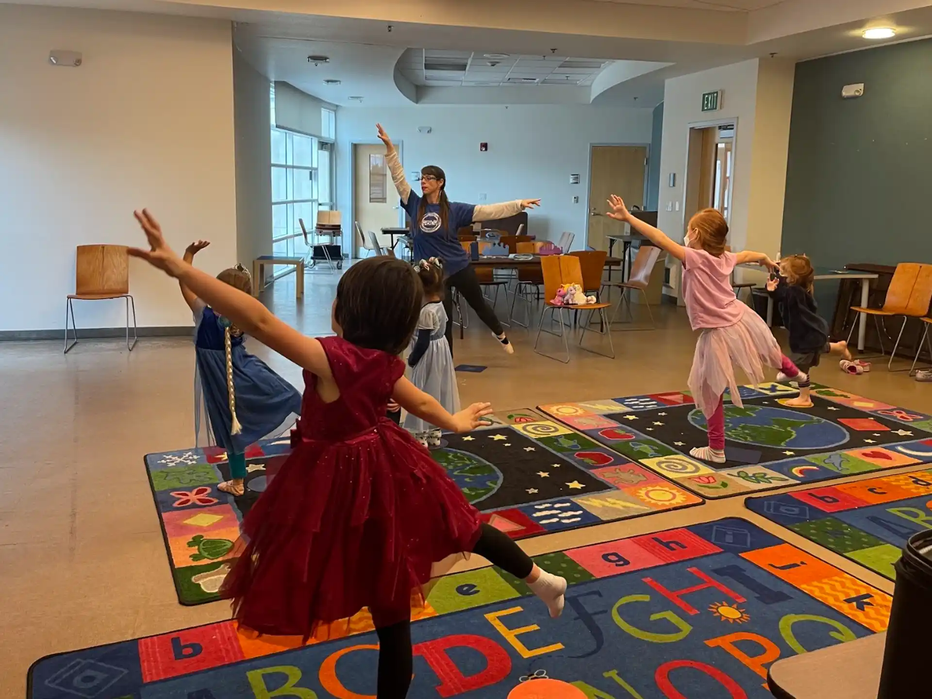 a group of children dancing on a rug in a room