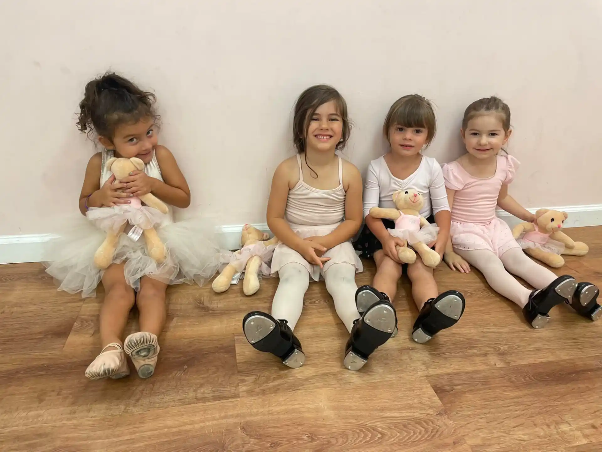 a group of children sitting on the floor holding stuffed animals