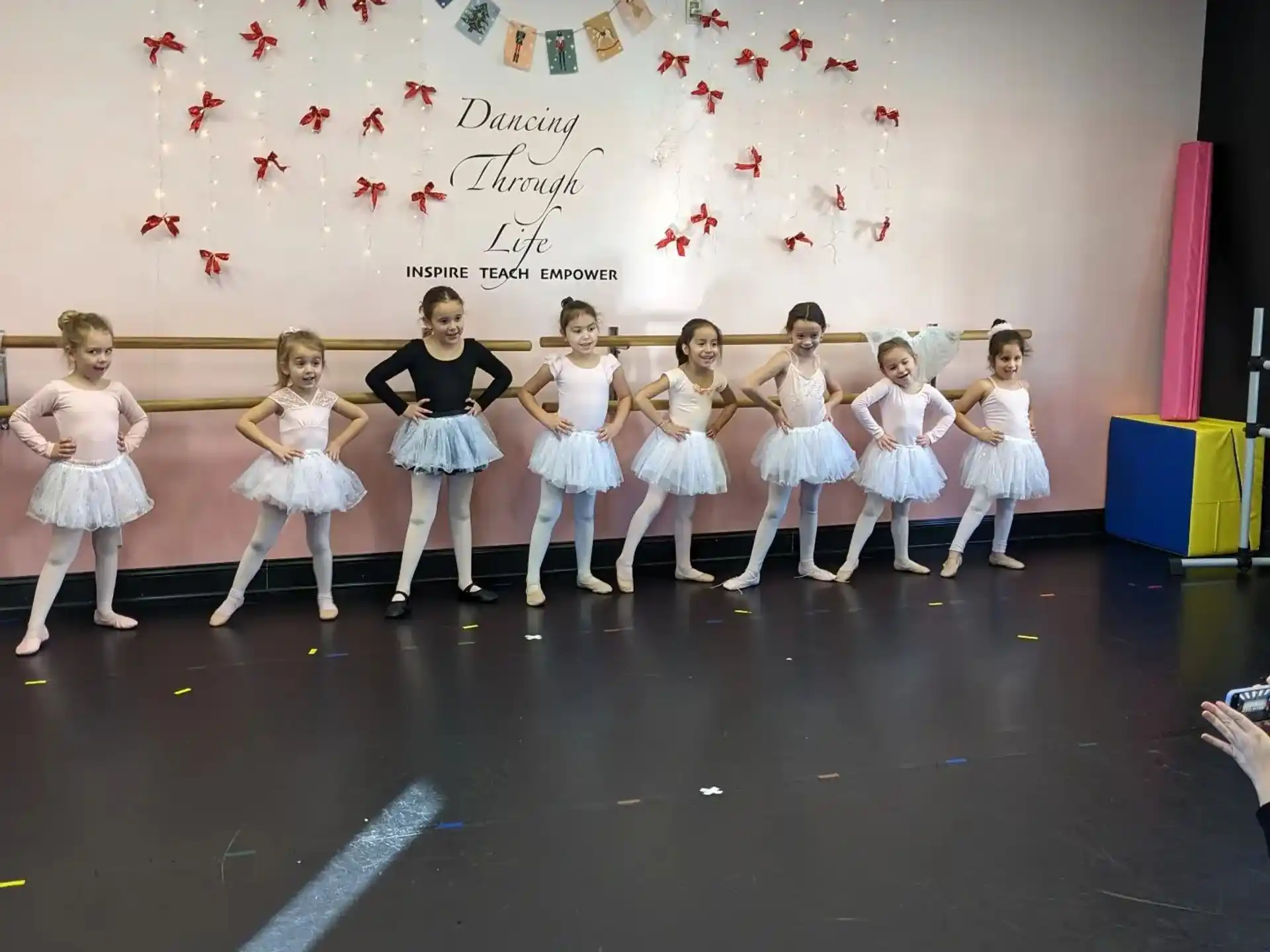 a group of girls in white dresses and skirts on a stage
