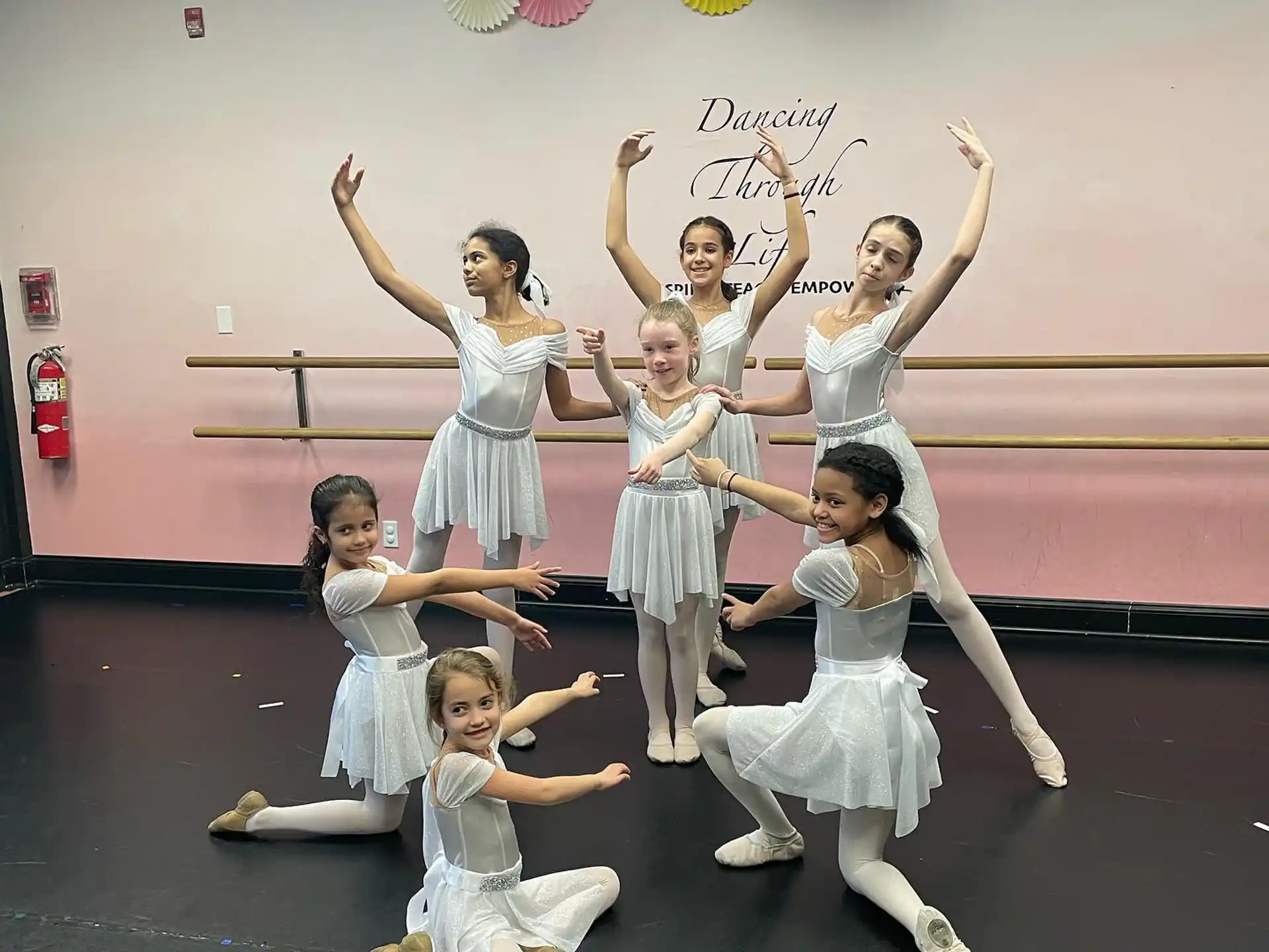 a group of girls in white dresses jumping in the air