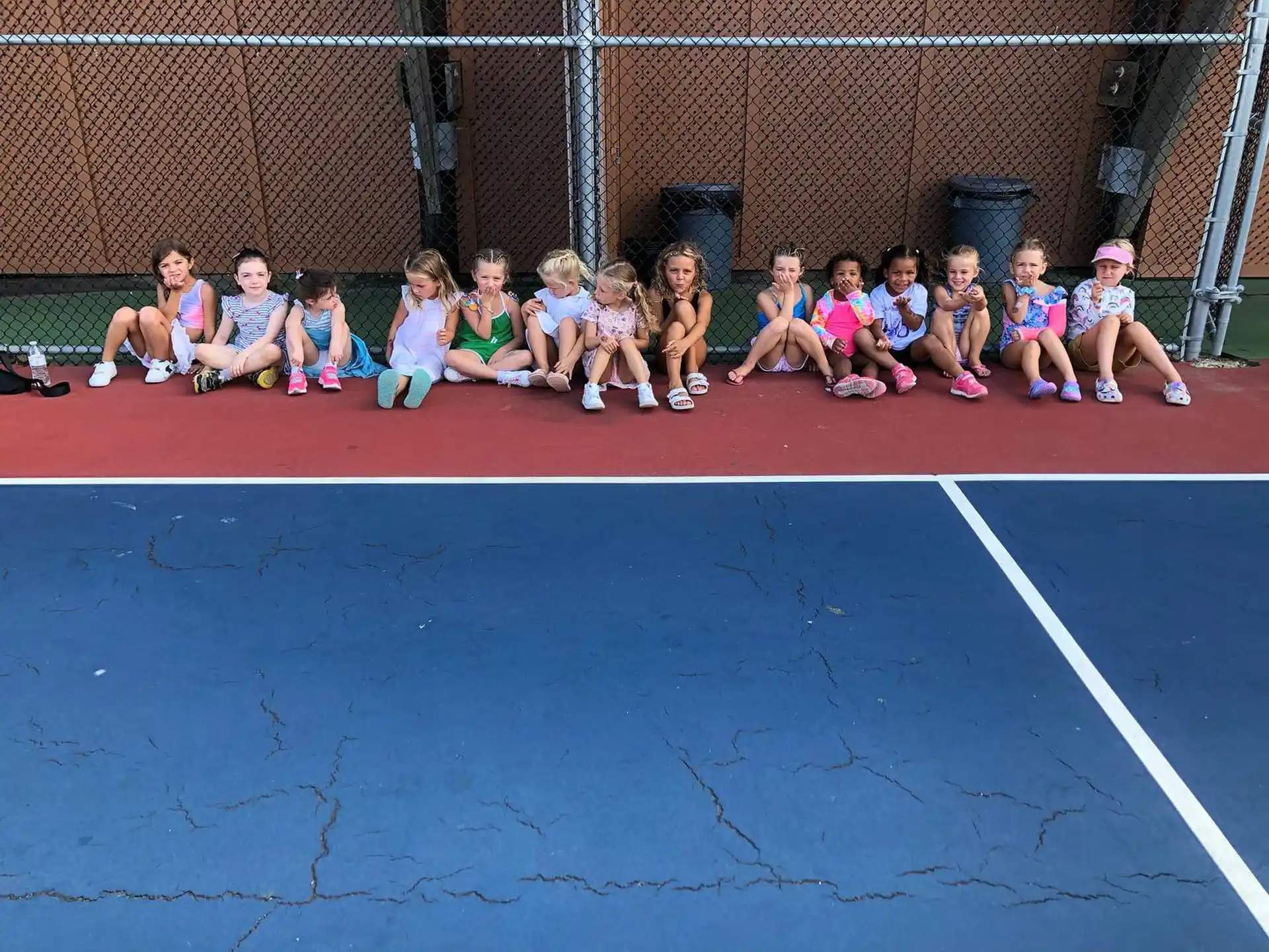 a group of children sitting on a mat on a court