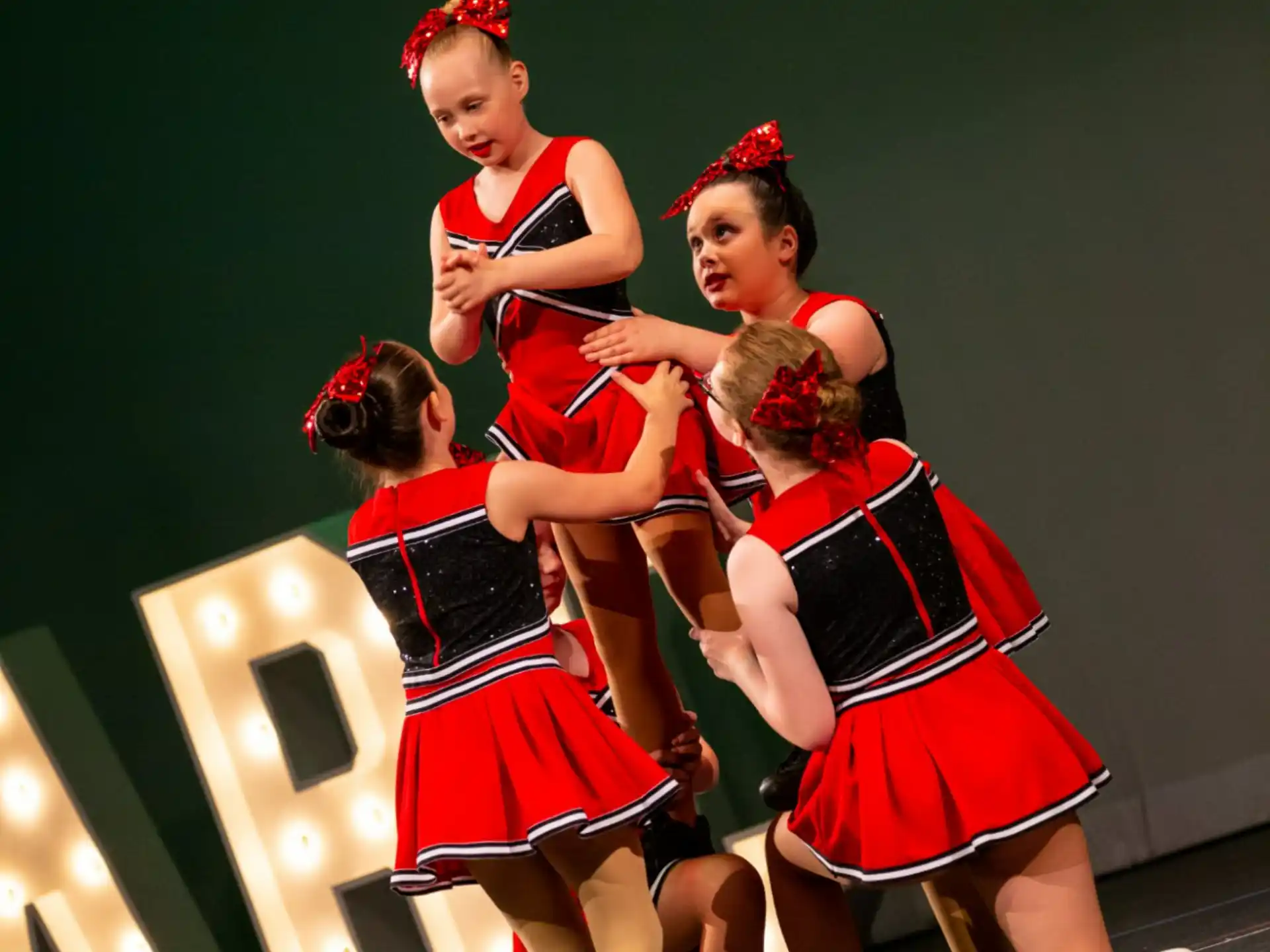 a group of girls in red and black dresses dancing on a stage