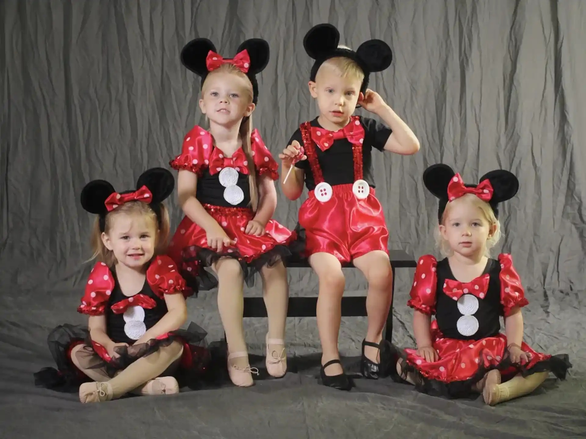 a group of girls in red and black dresses sitting on the floor
