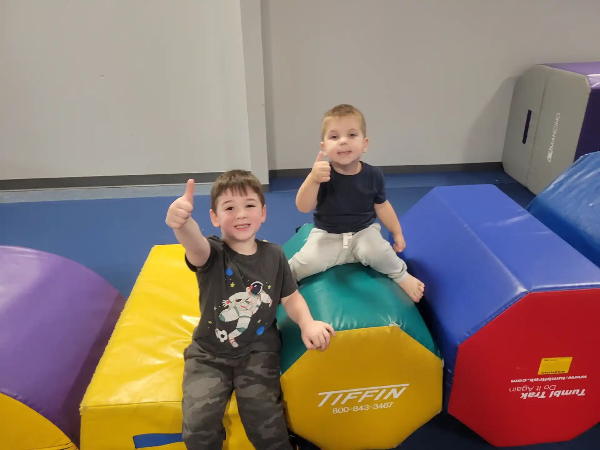 two boys sitting on a large yellow and blue toy