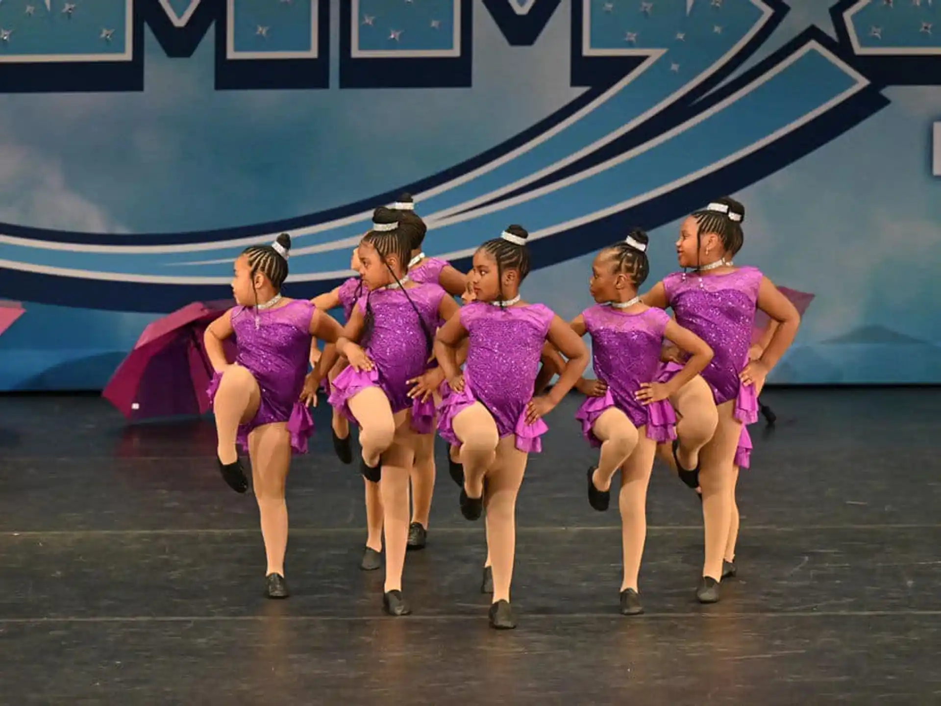 a group of women in purple dresses dancing on a stage