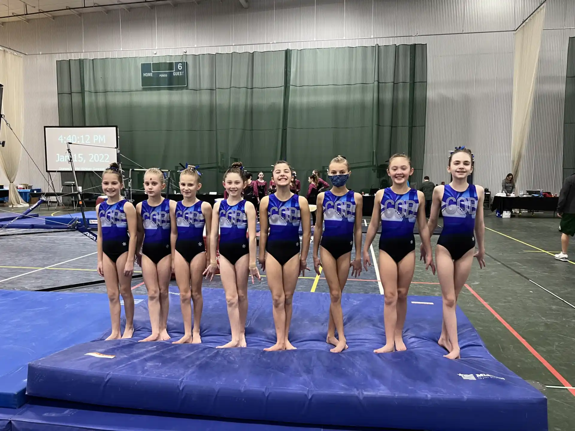 a group of women in blue swimsuits standing on a mat