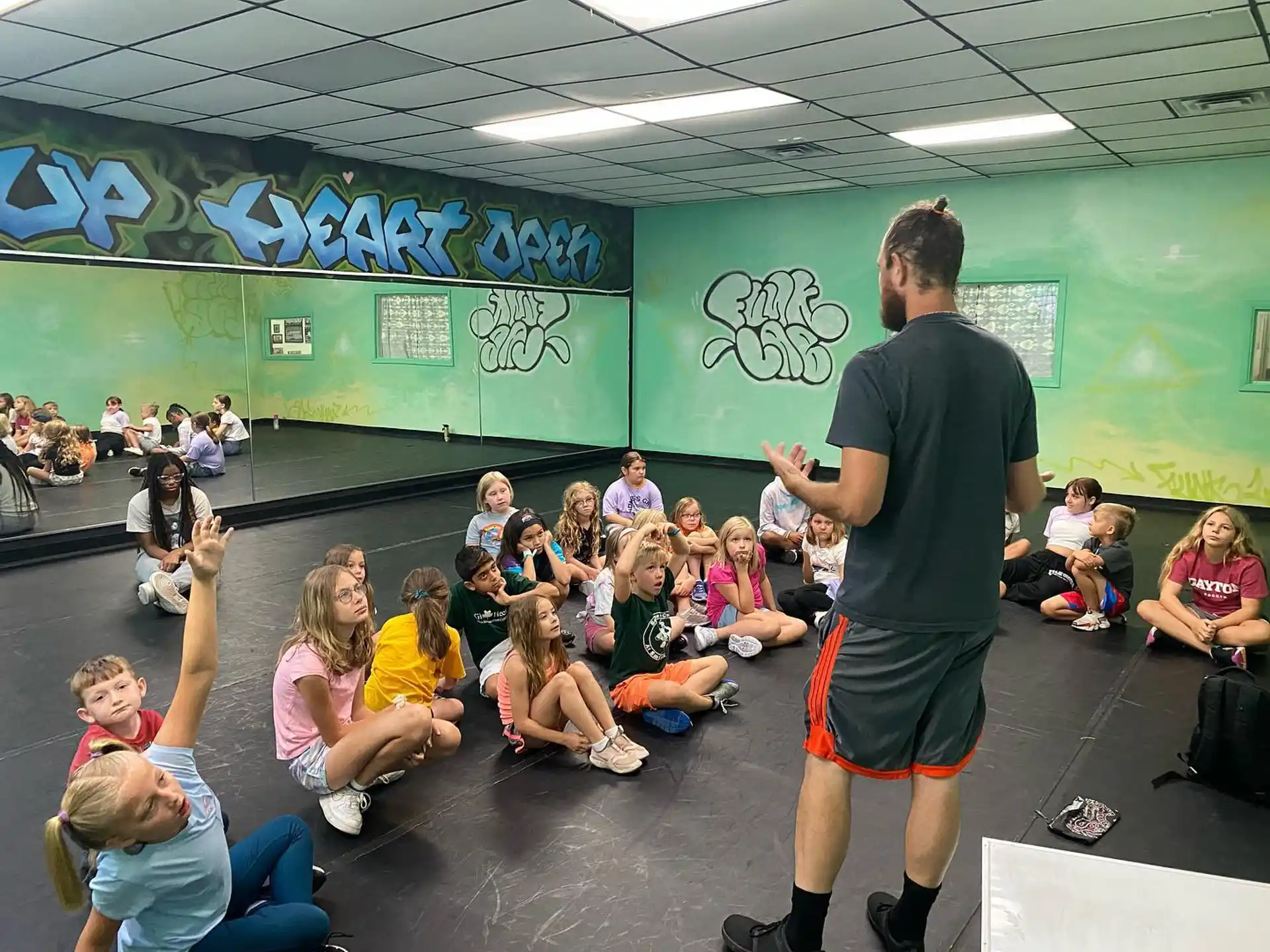 a person standing in front of a group of children sitting on the floor