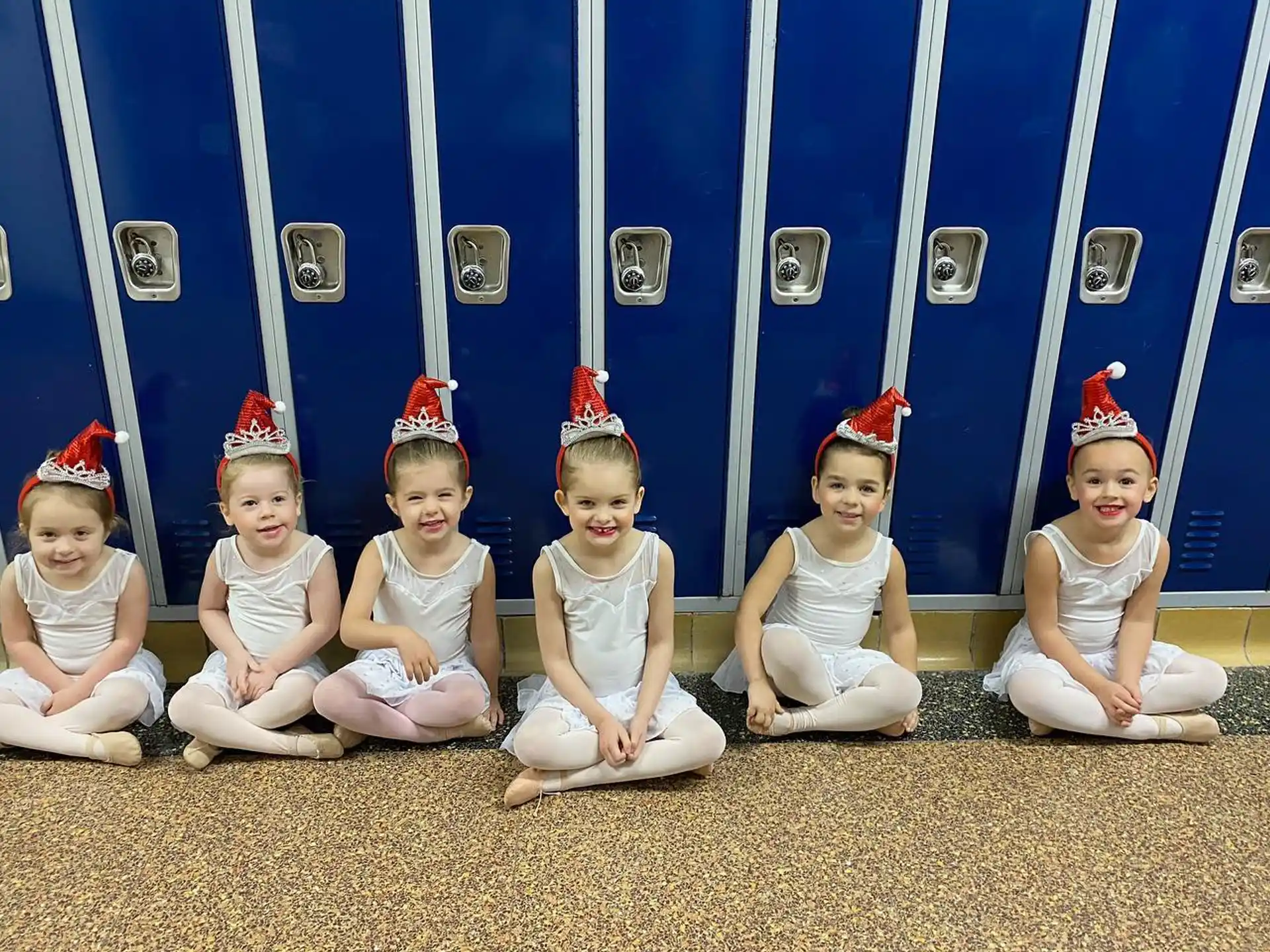 a group of children wearing white and red hats sitting on the ground