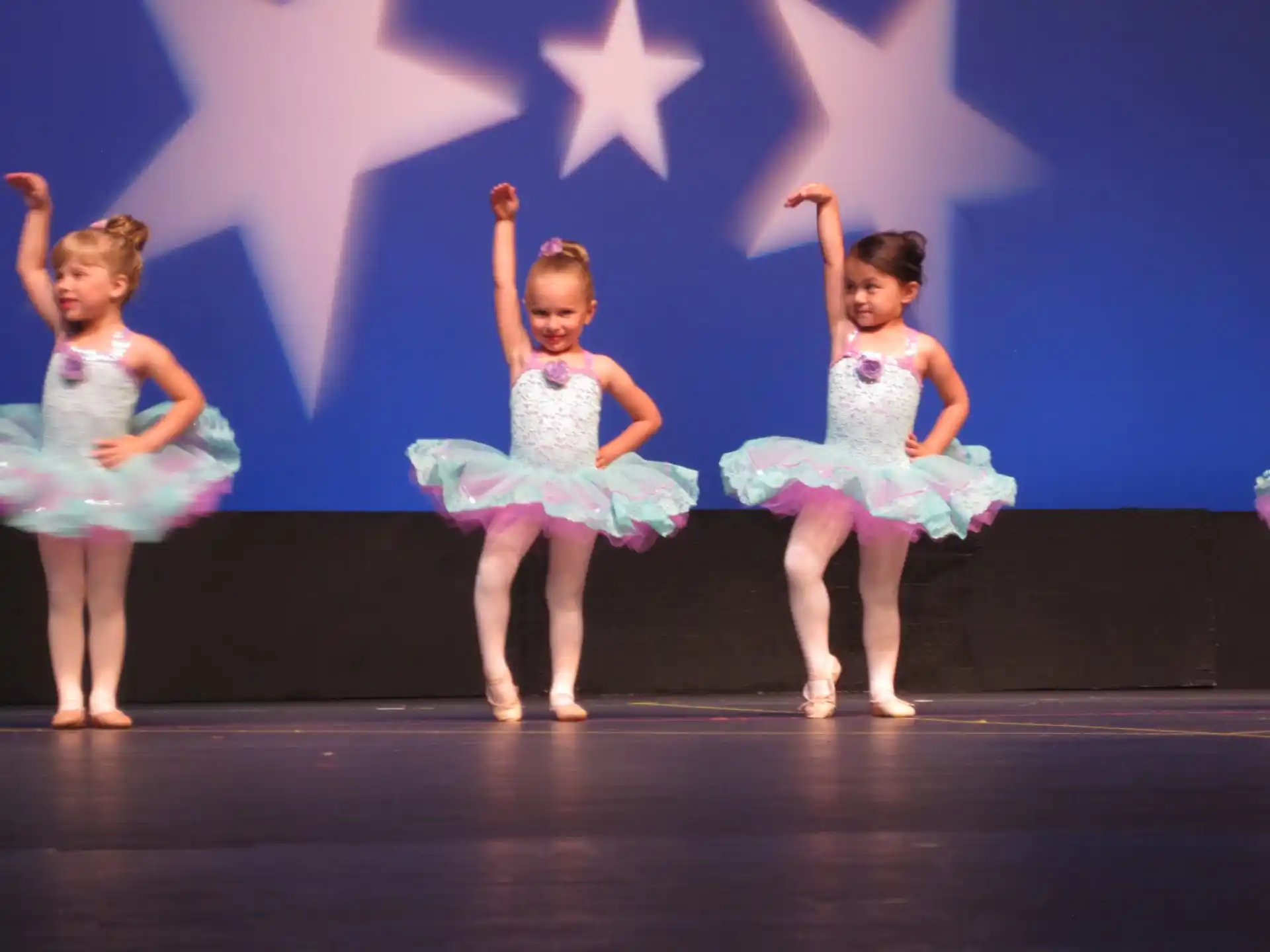 a group of girls in dresses dancing on a stage