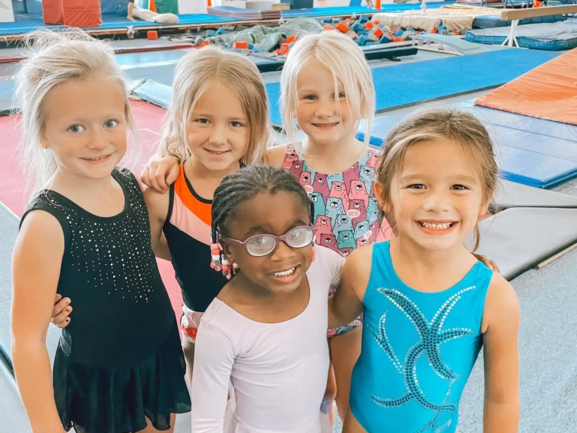 a group of girls posing for a photo in front of a swimming pool