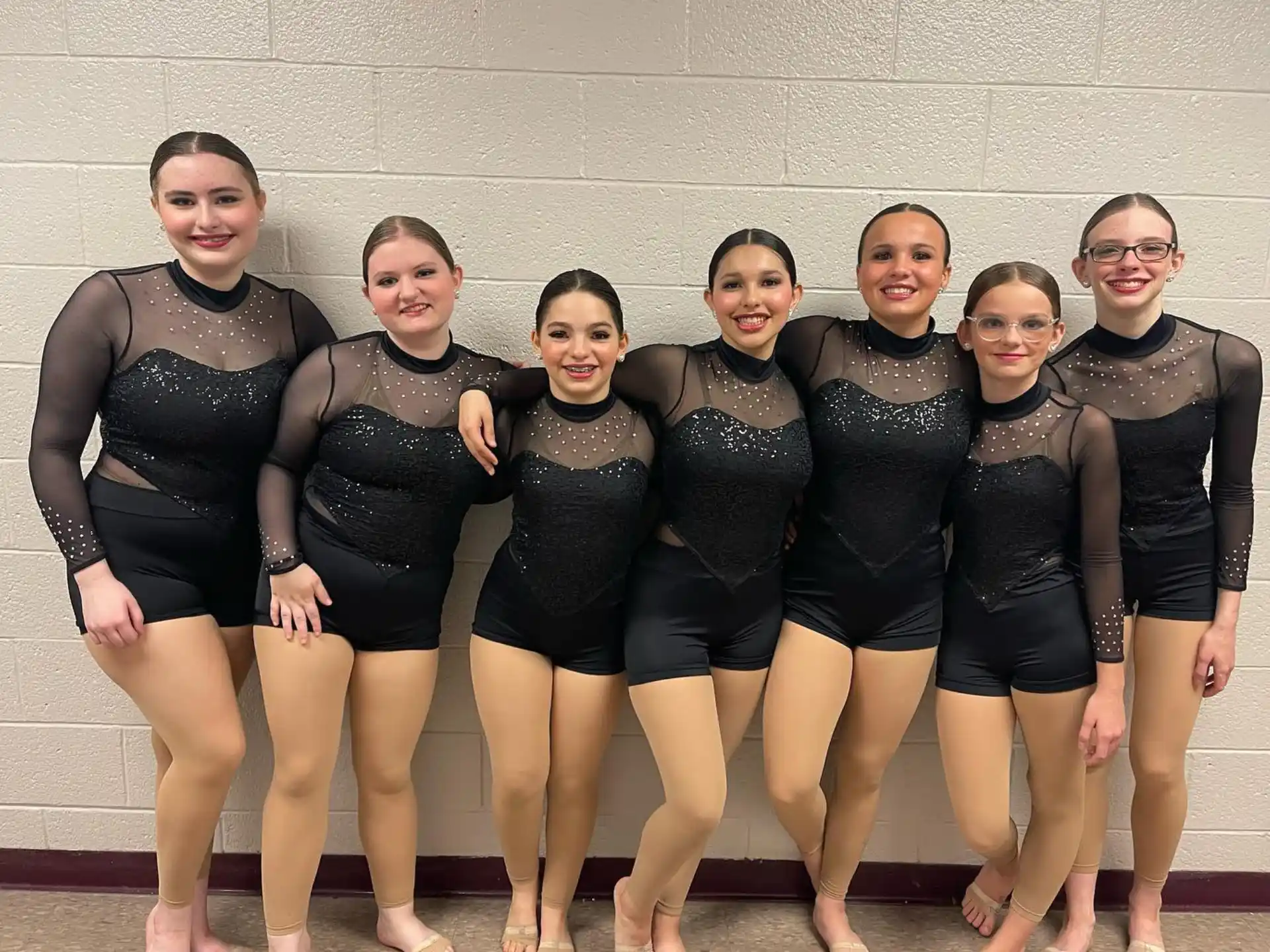 a group of women in black leotards posing for a photo