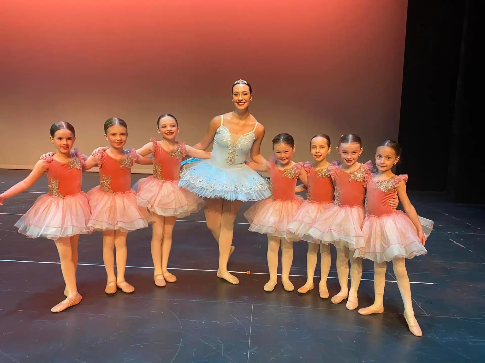 a group of girls in dresses and skirts on a stage
