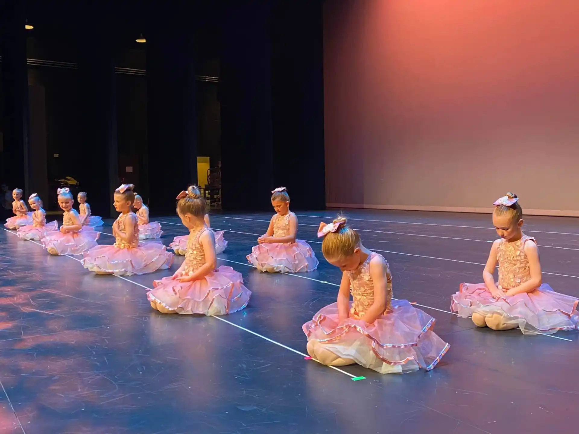 a group of girls in dresses on a stage