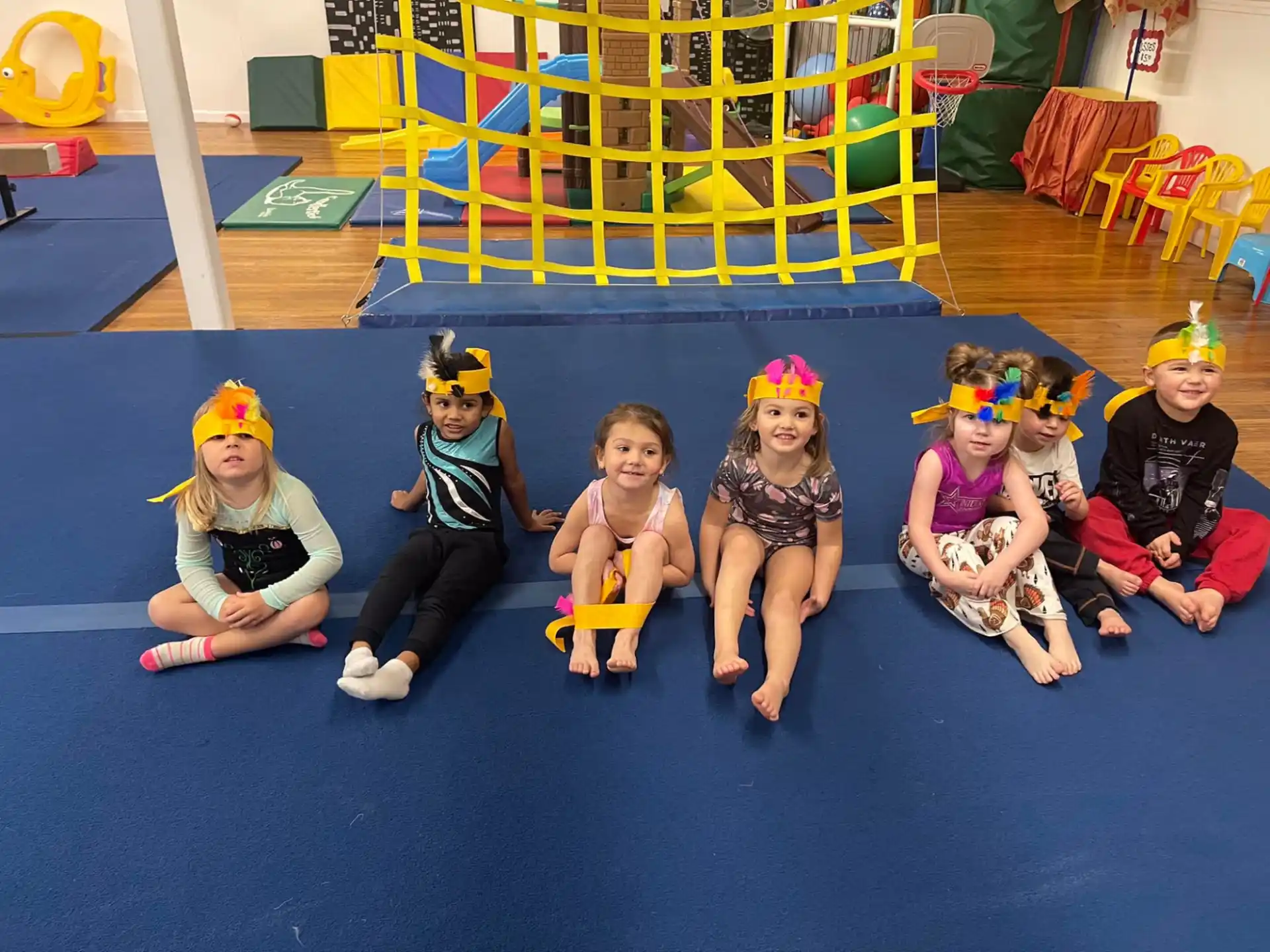 a group of children sitting on the floor wearing clothing