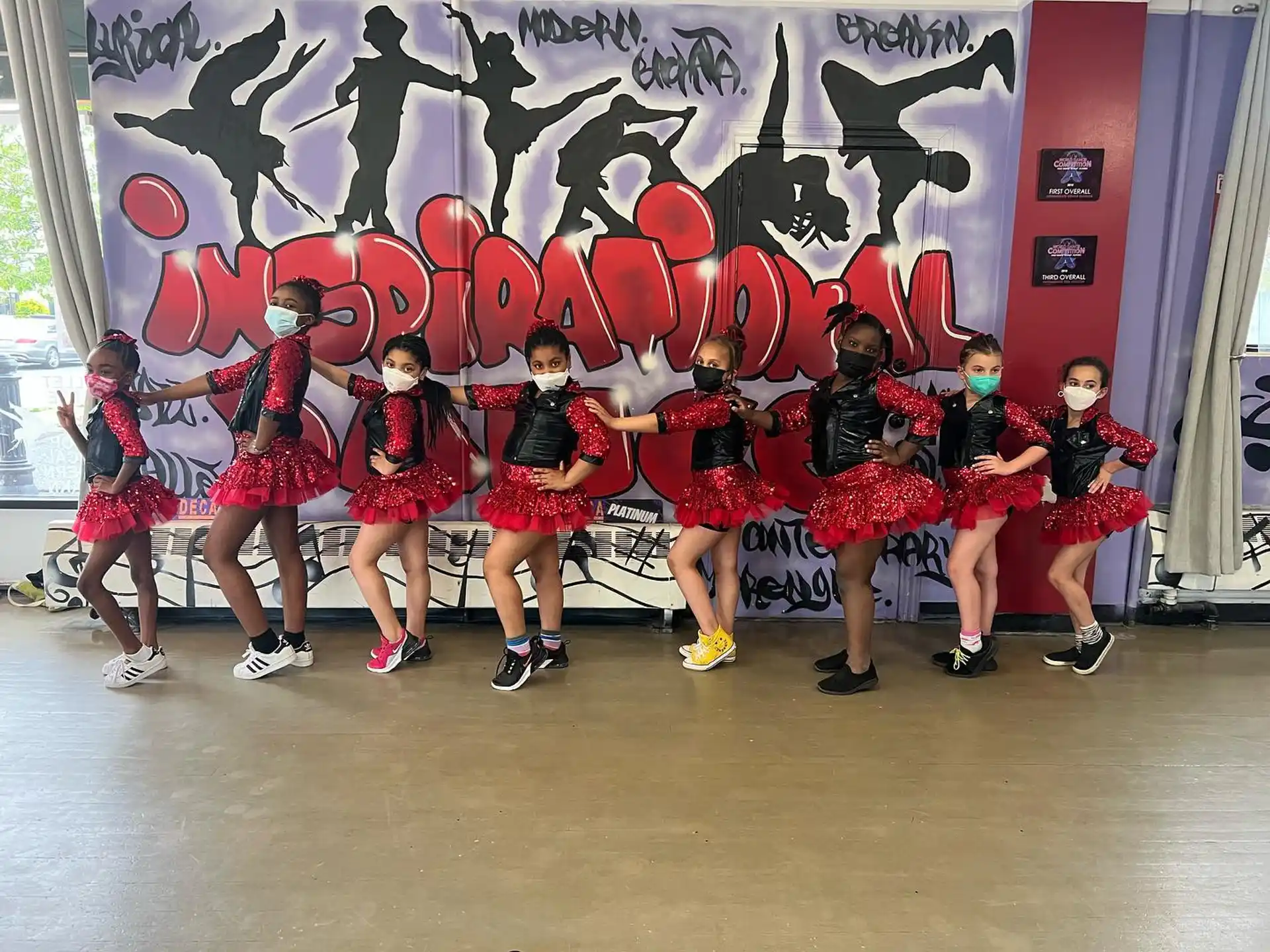 a group of girls in red and black dresses on a stage