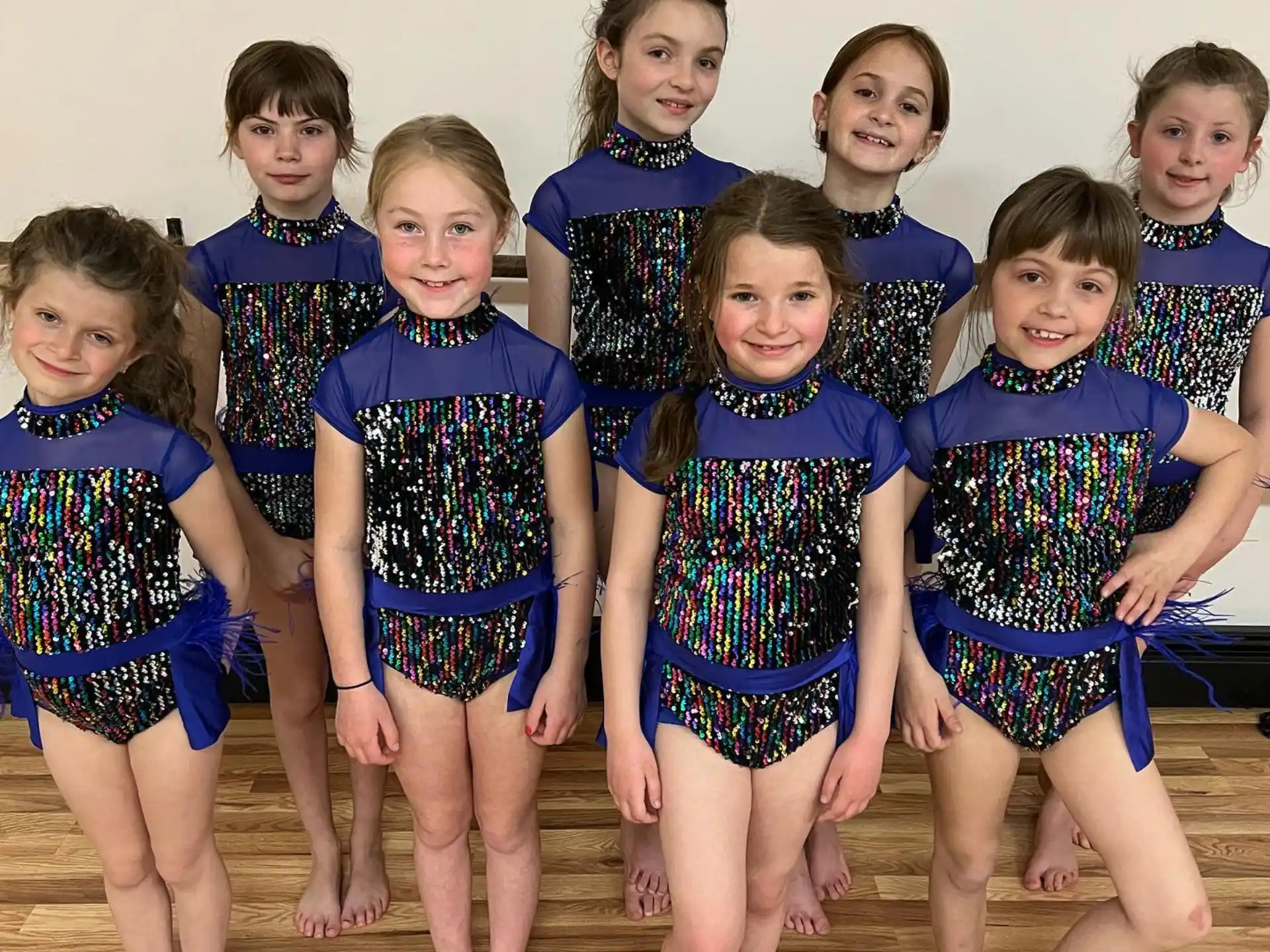 a group of girls in matching blue and black dresses