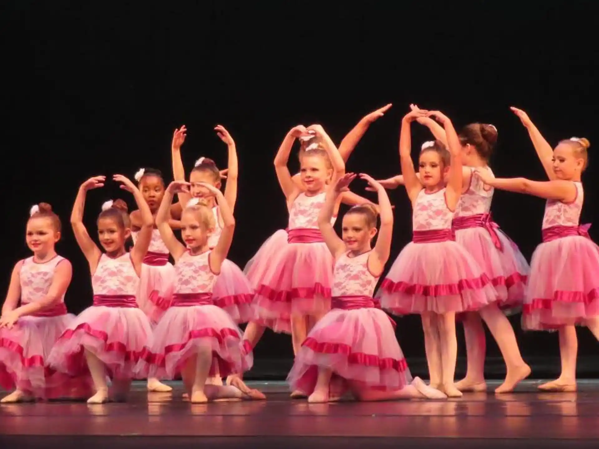 a group of girls in dresses on a stage