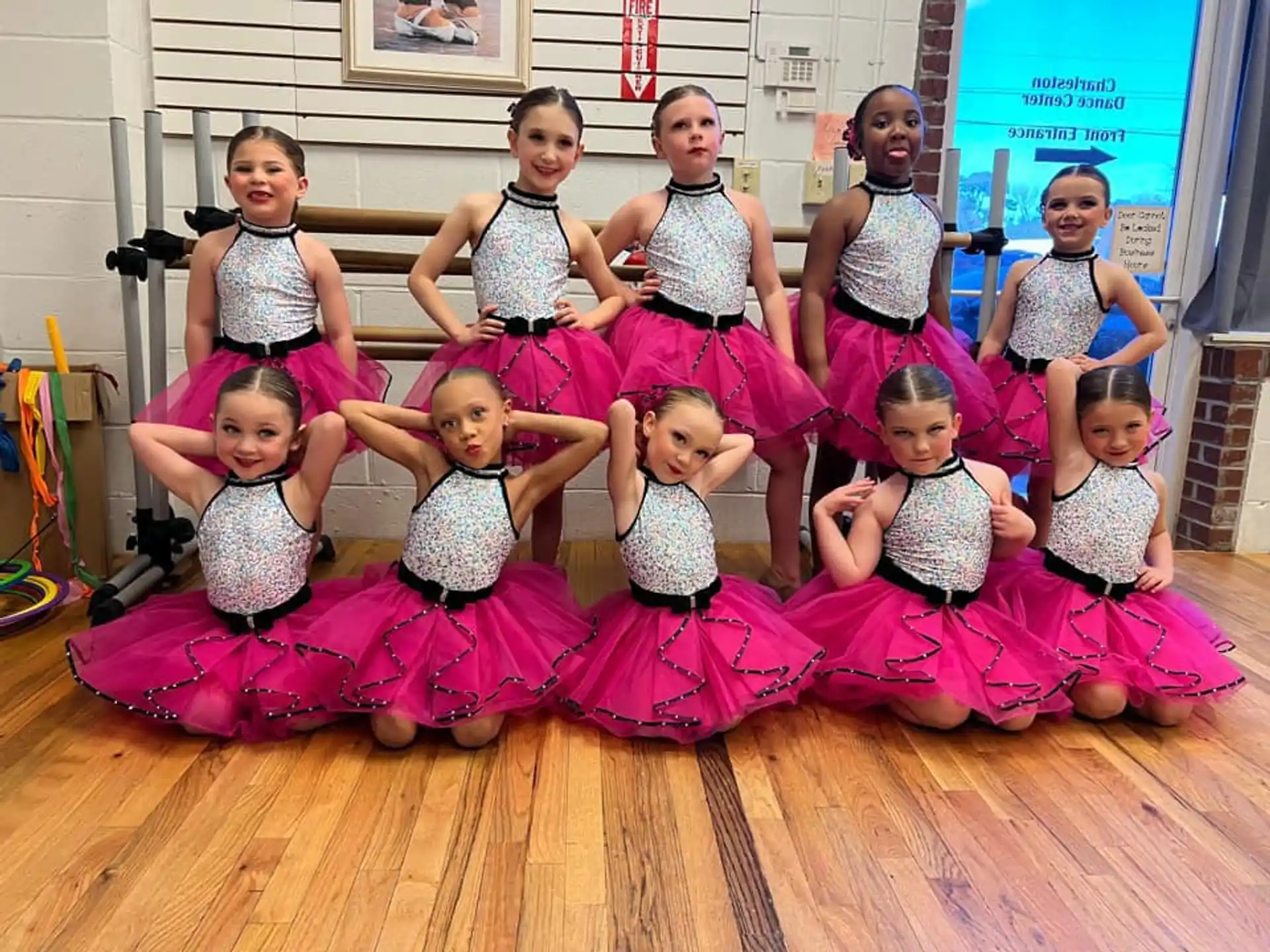 a group of girls sitting on the floor posing for a photo