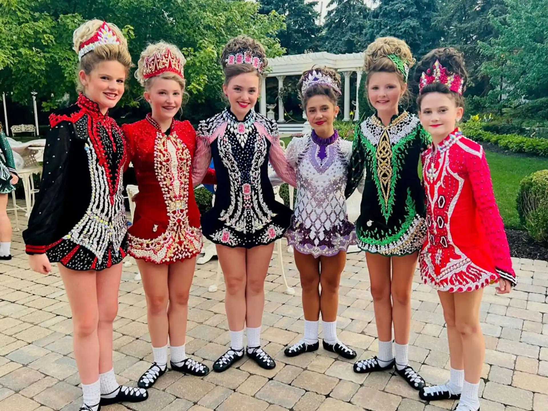 a group of girls in dresses and hats posing for a photo