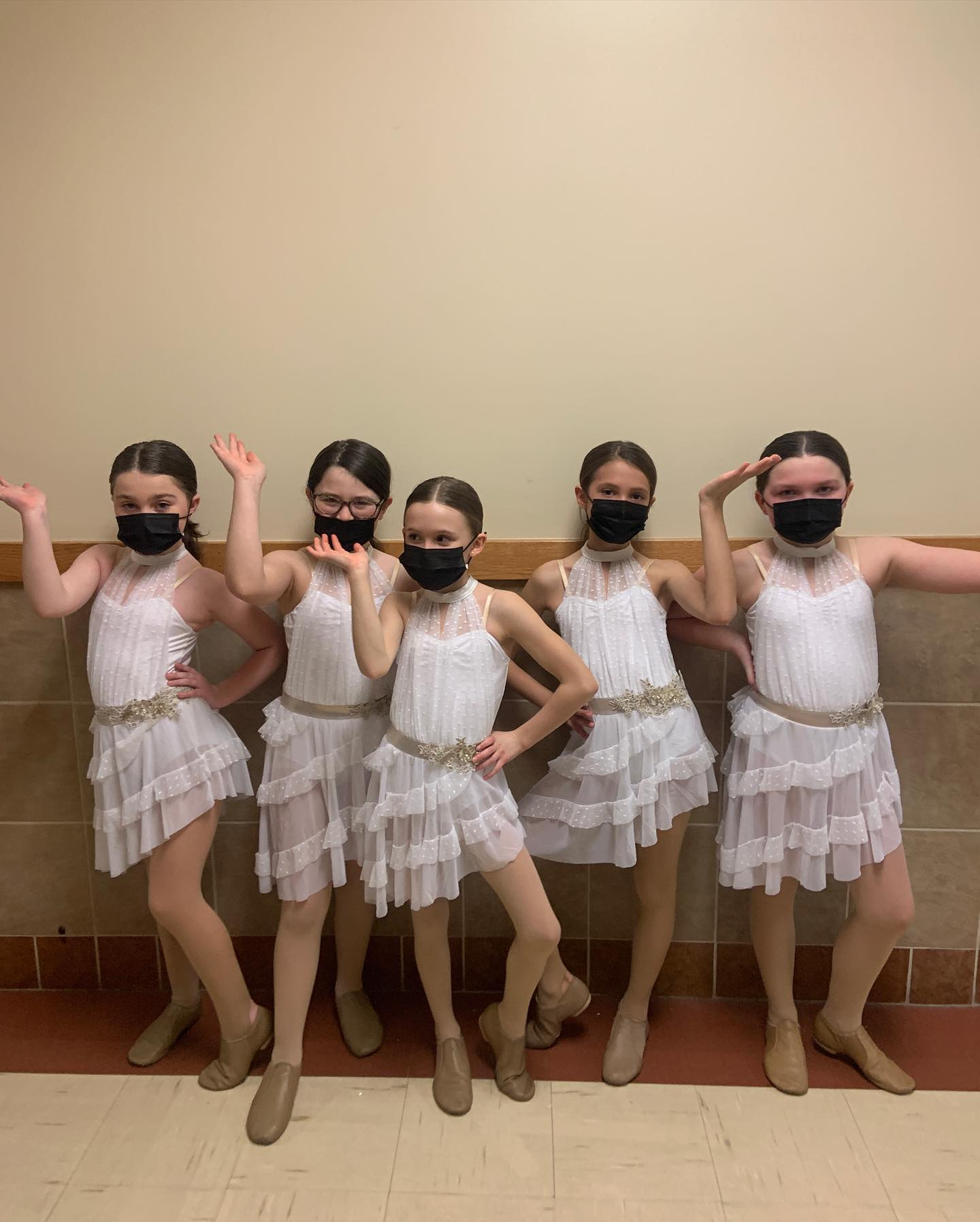 a group of girls wearing white dresses and posing for a photo