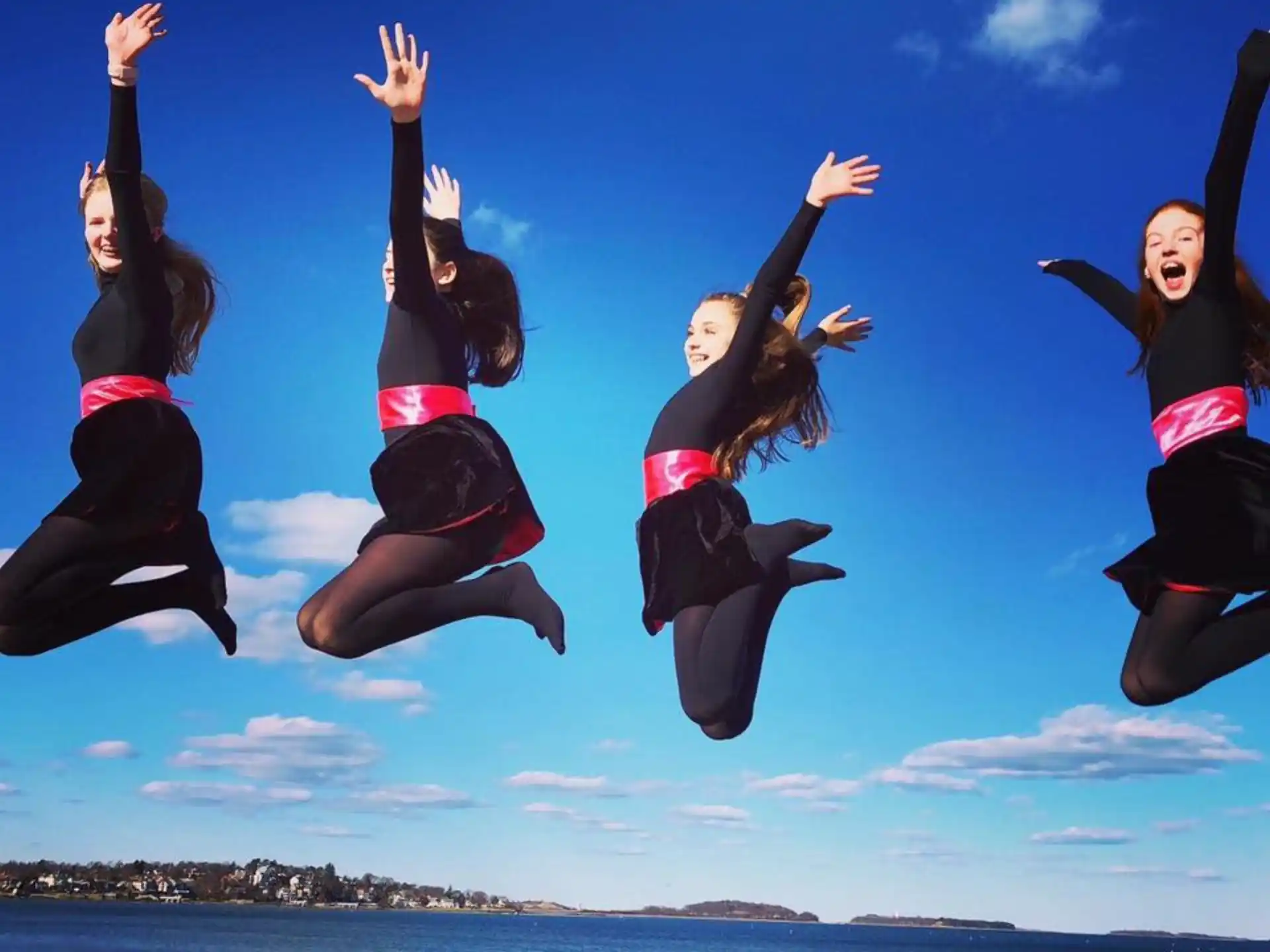 a group of women jumping in the air on a beach