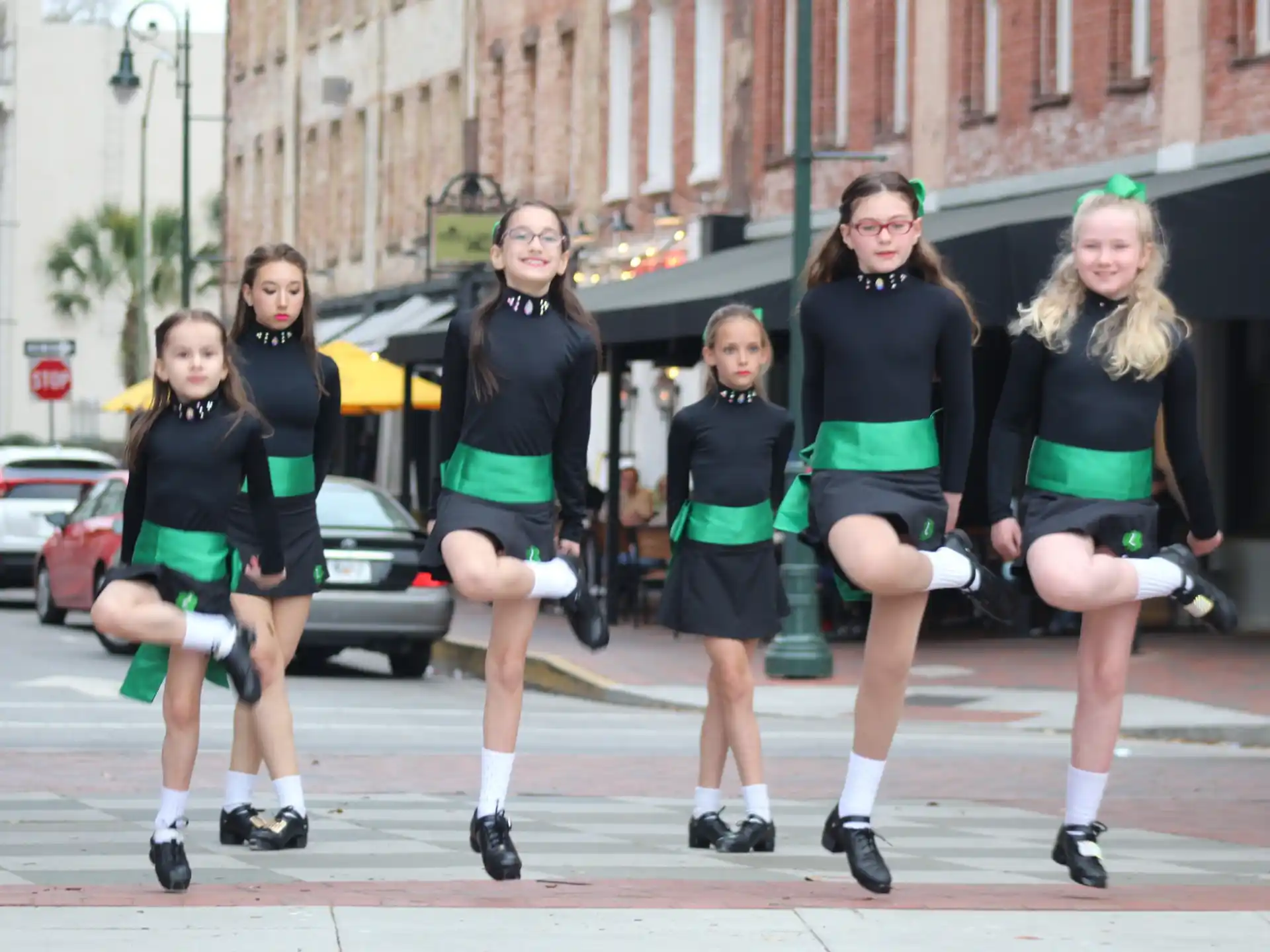 a group of women wearing matching black shirts and running on a street