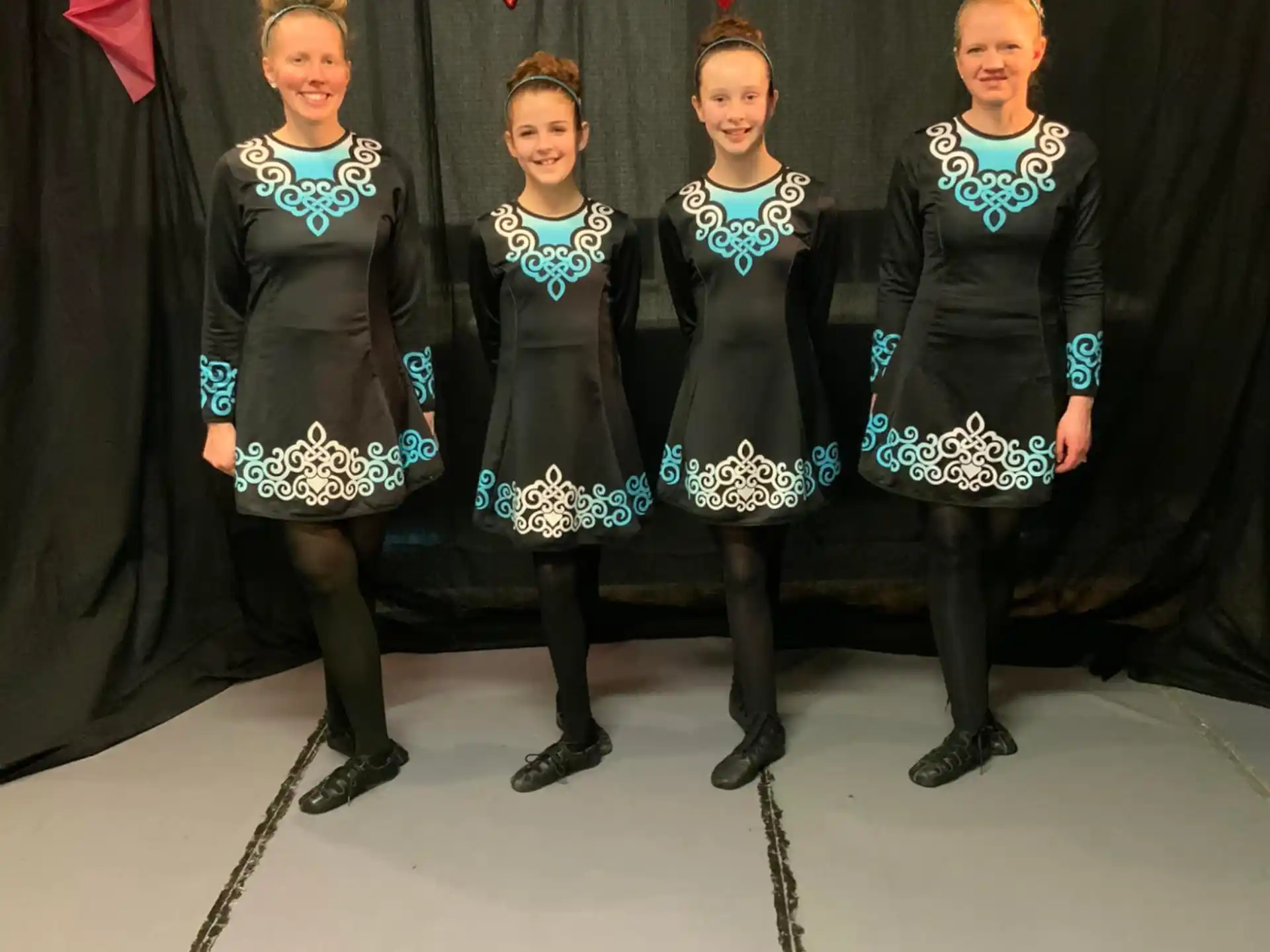 a group of women in black and white dresses standing in front of a curtain