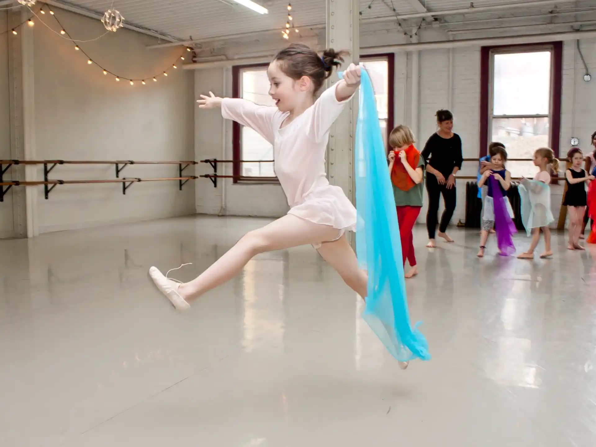 a girl dancing in a room with other children