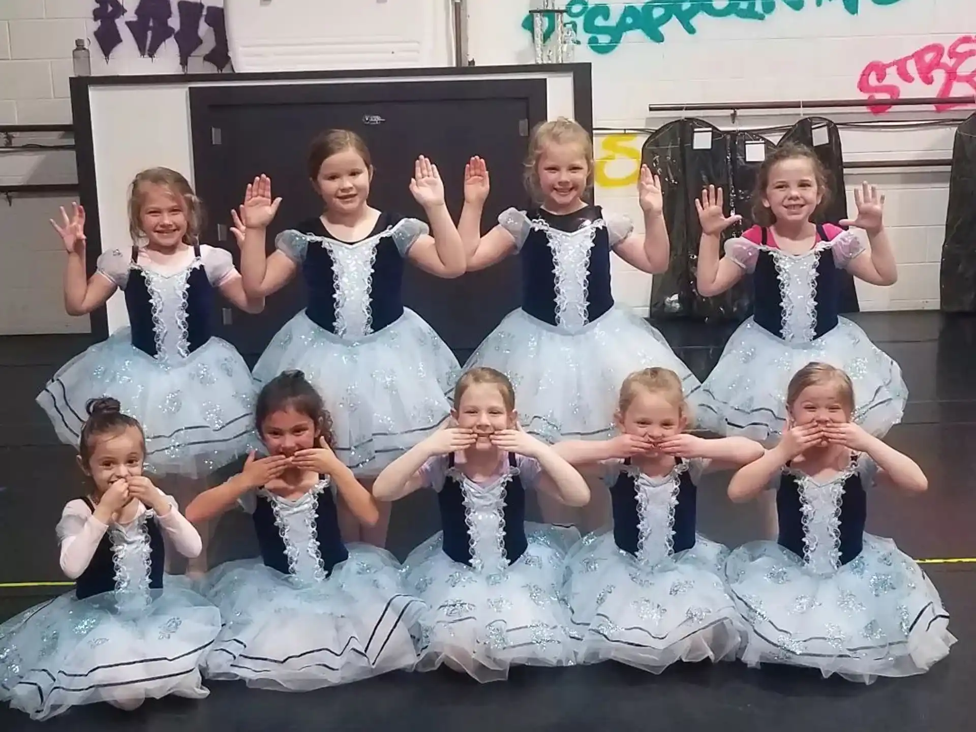a group of girls in blue and white dresses on a stage