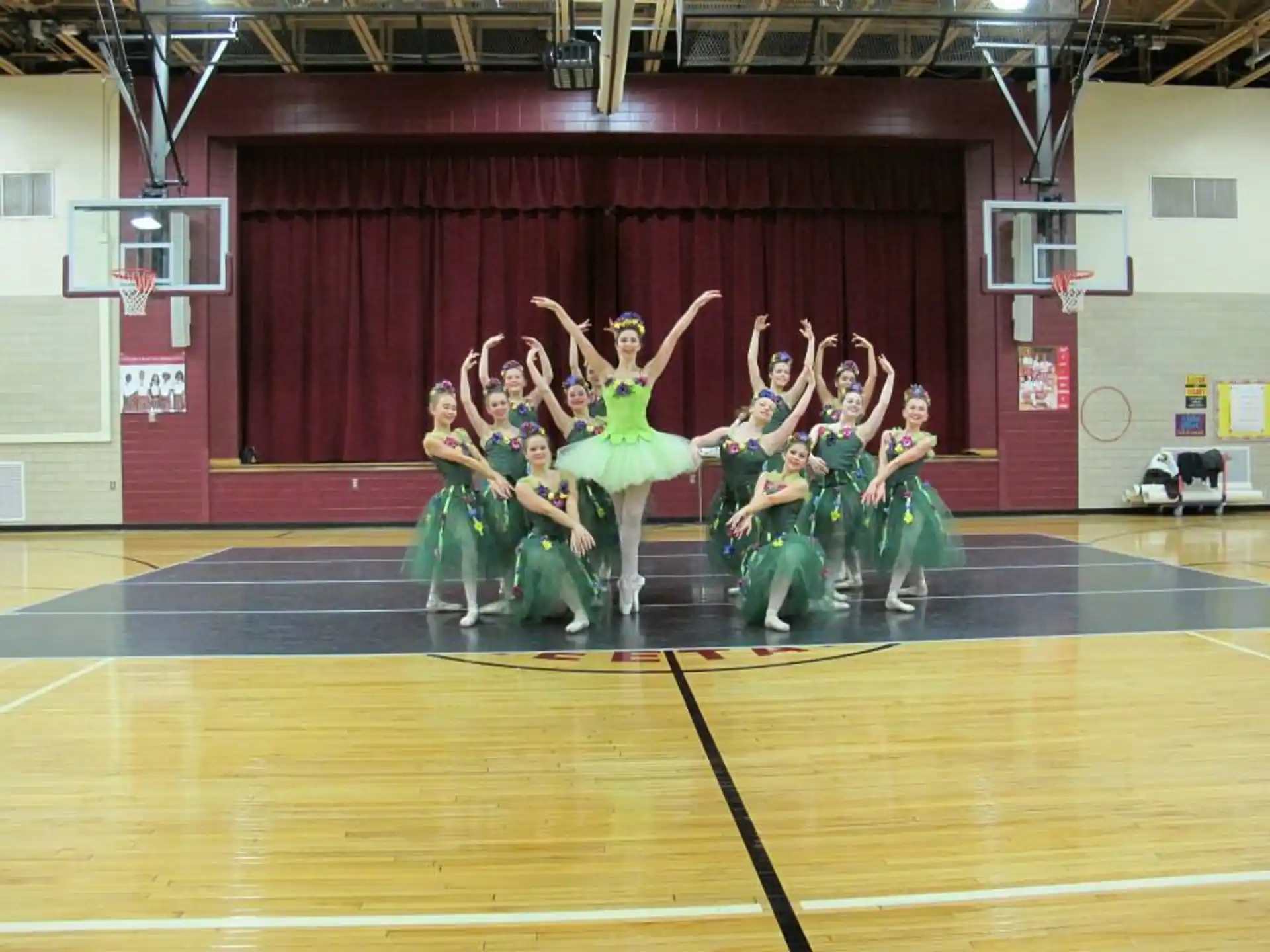 a group of girls in green dresses dancing on a basketball court