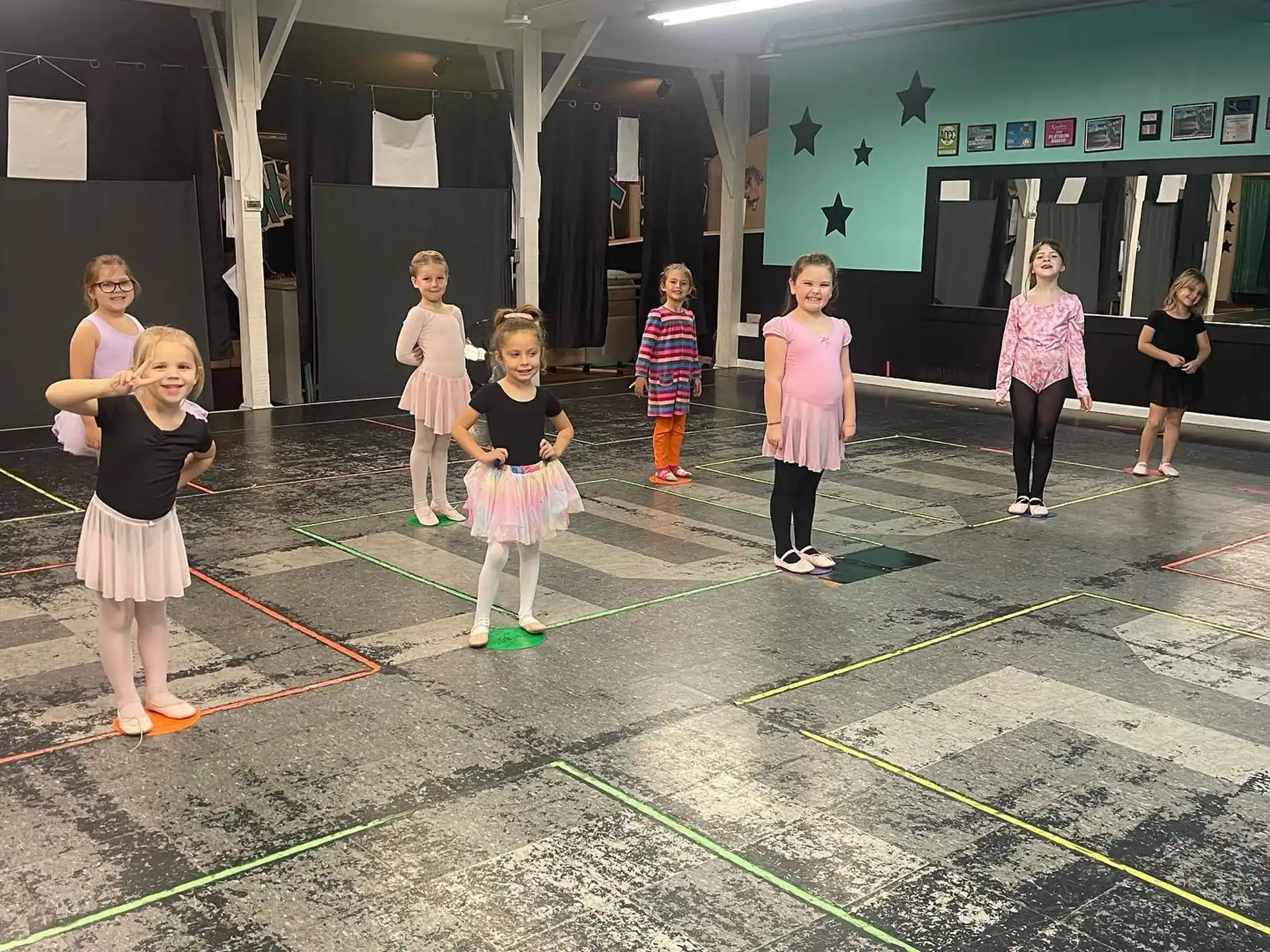 a group of children standing in a room with a green floor