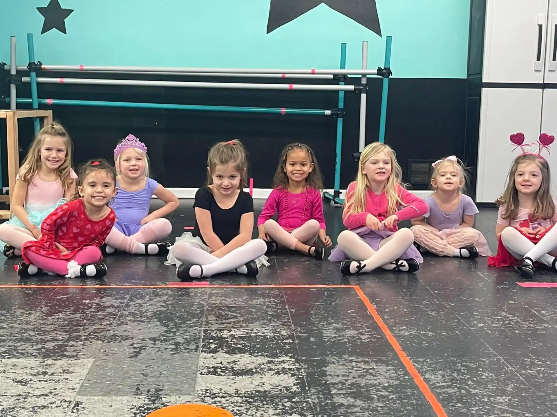 a group of girls sitting on the ground posing for a photo