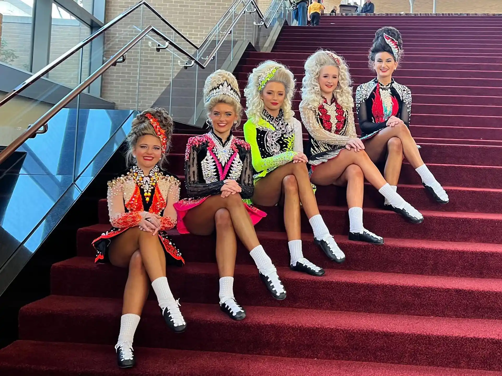 a group of girls sitting on a red carpet