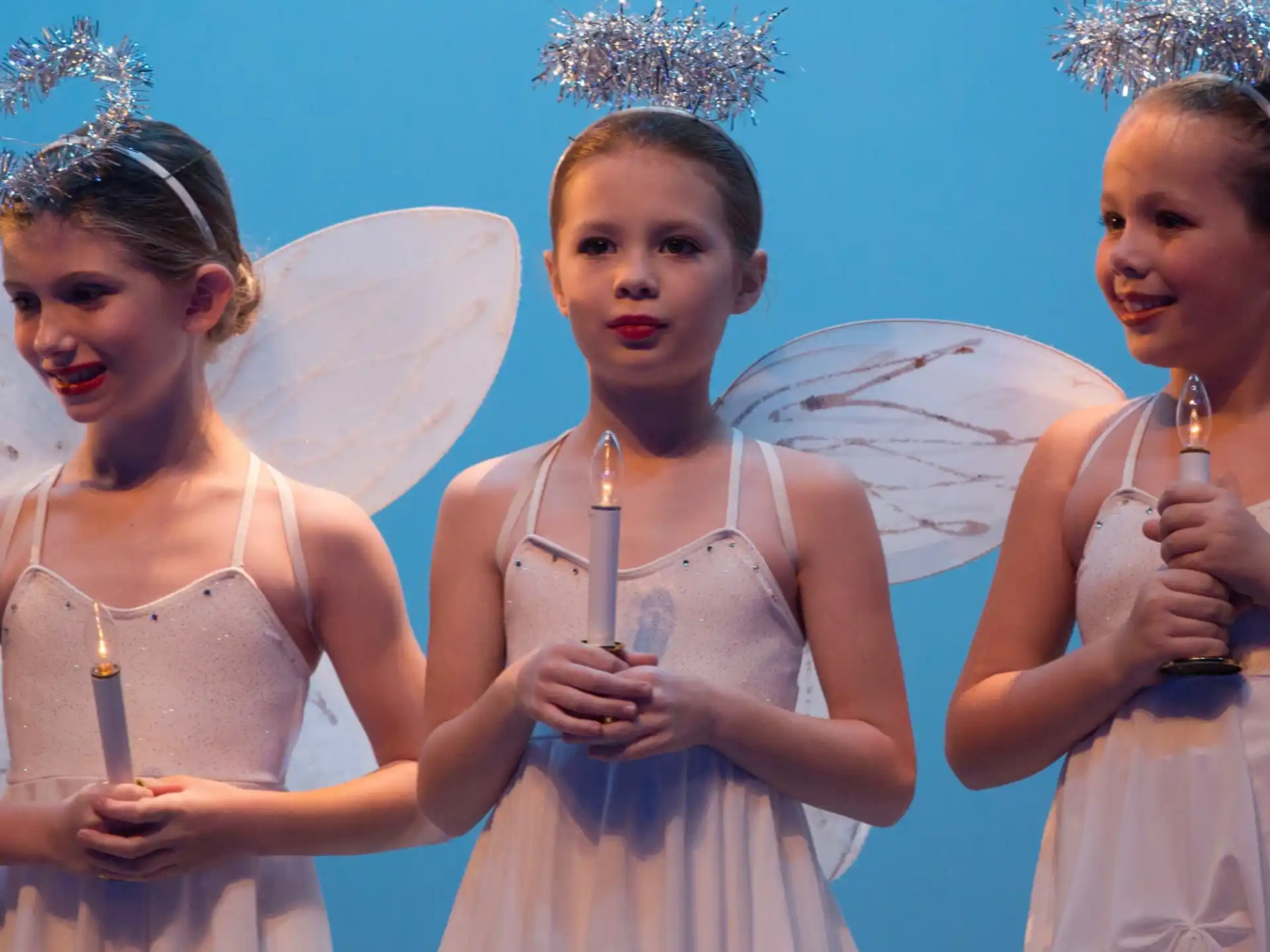a group of girls wearing white dresses and holding a microphone