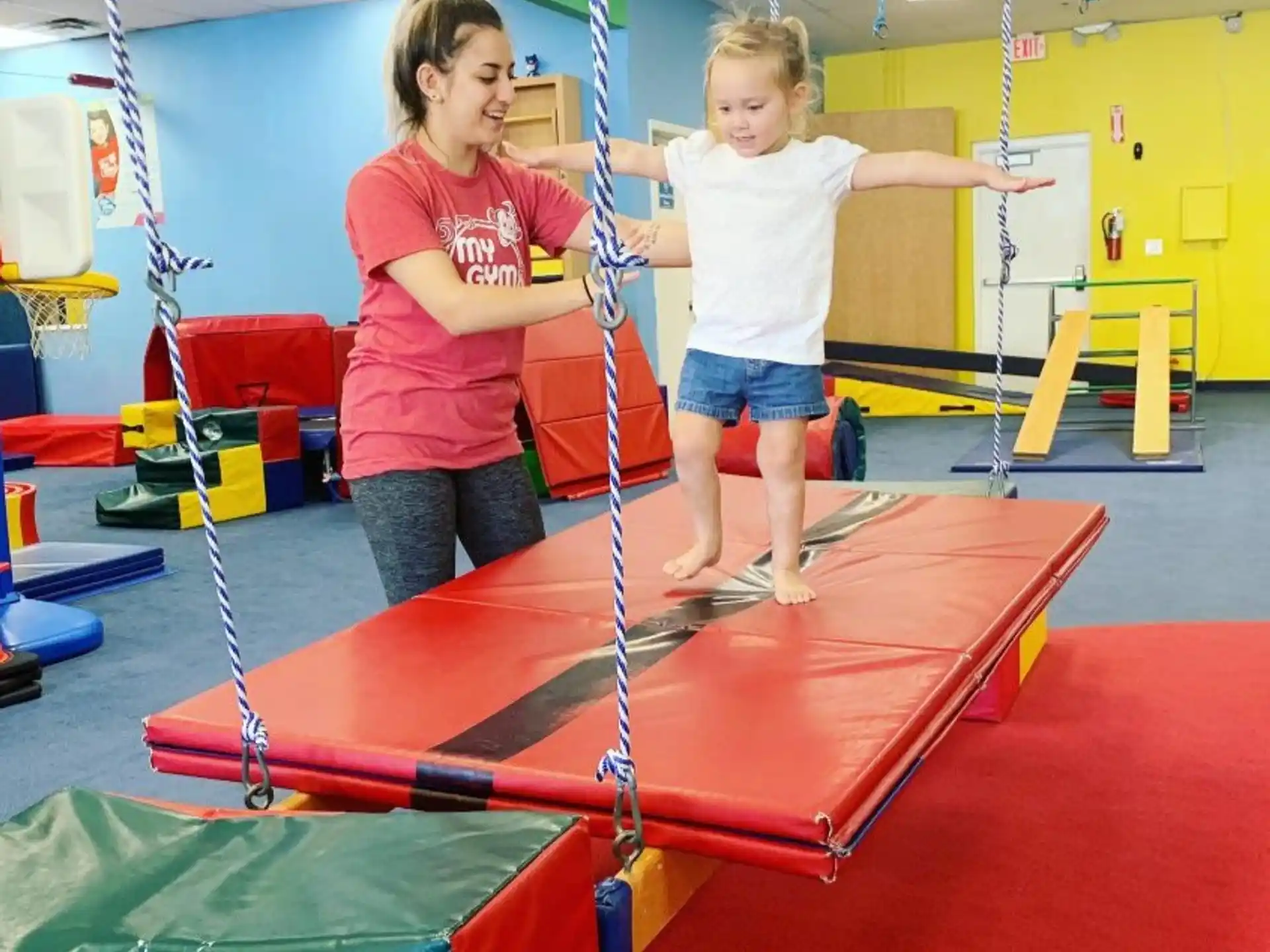 a couple of girls playing on a trampoline in a gym
