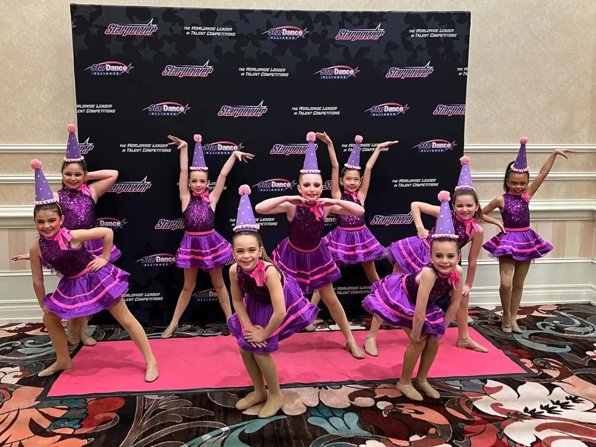 a group of girls in purple and white dancing on a stage