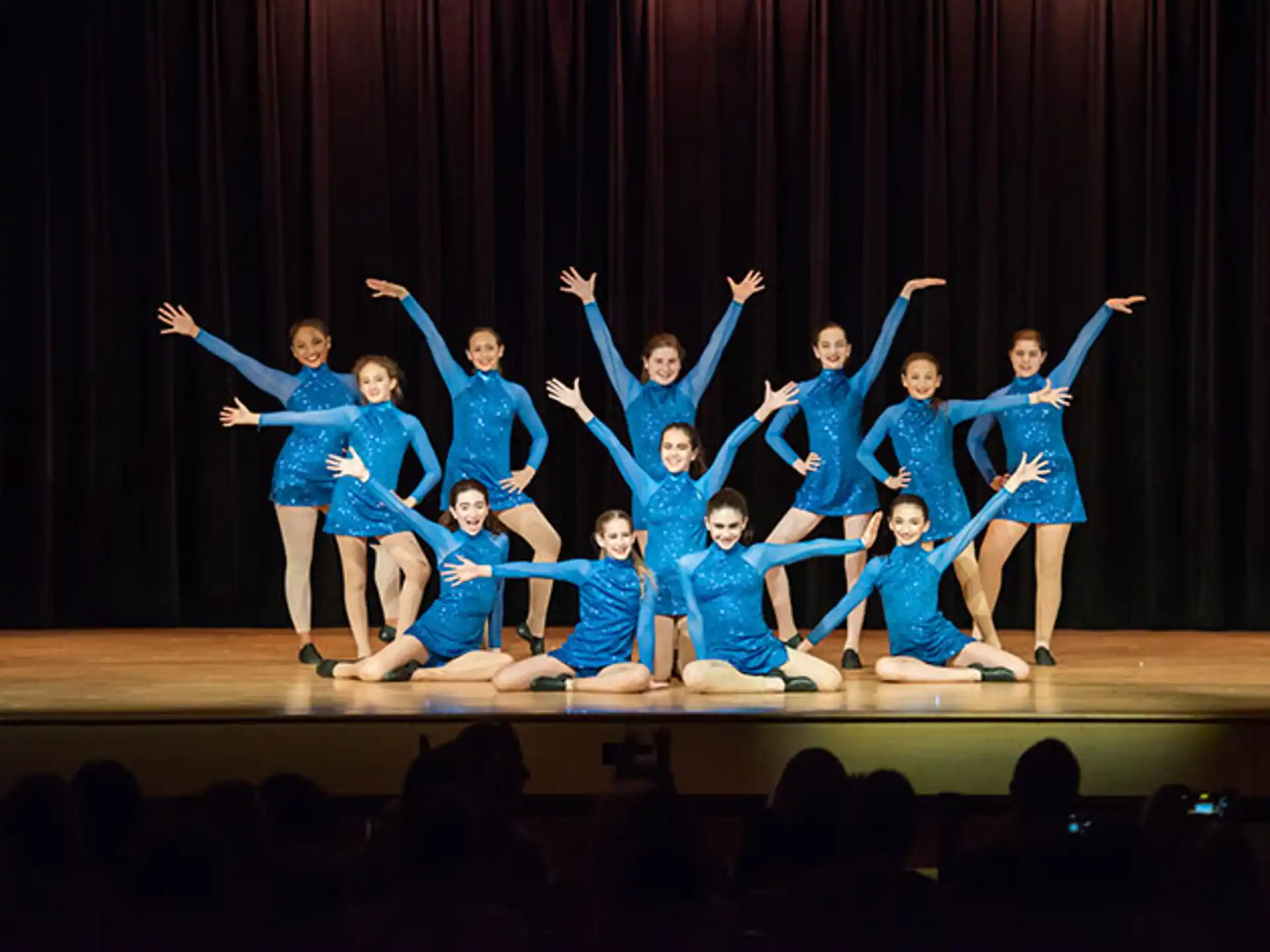 a group of girls in blue dress dancing on a stage