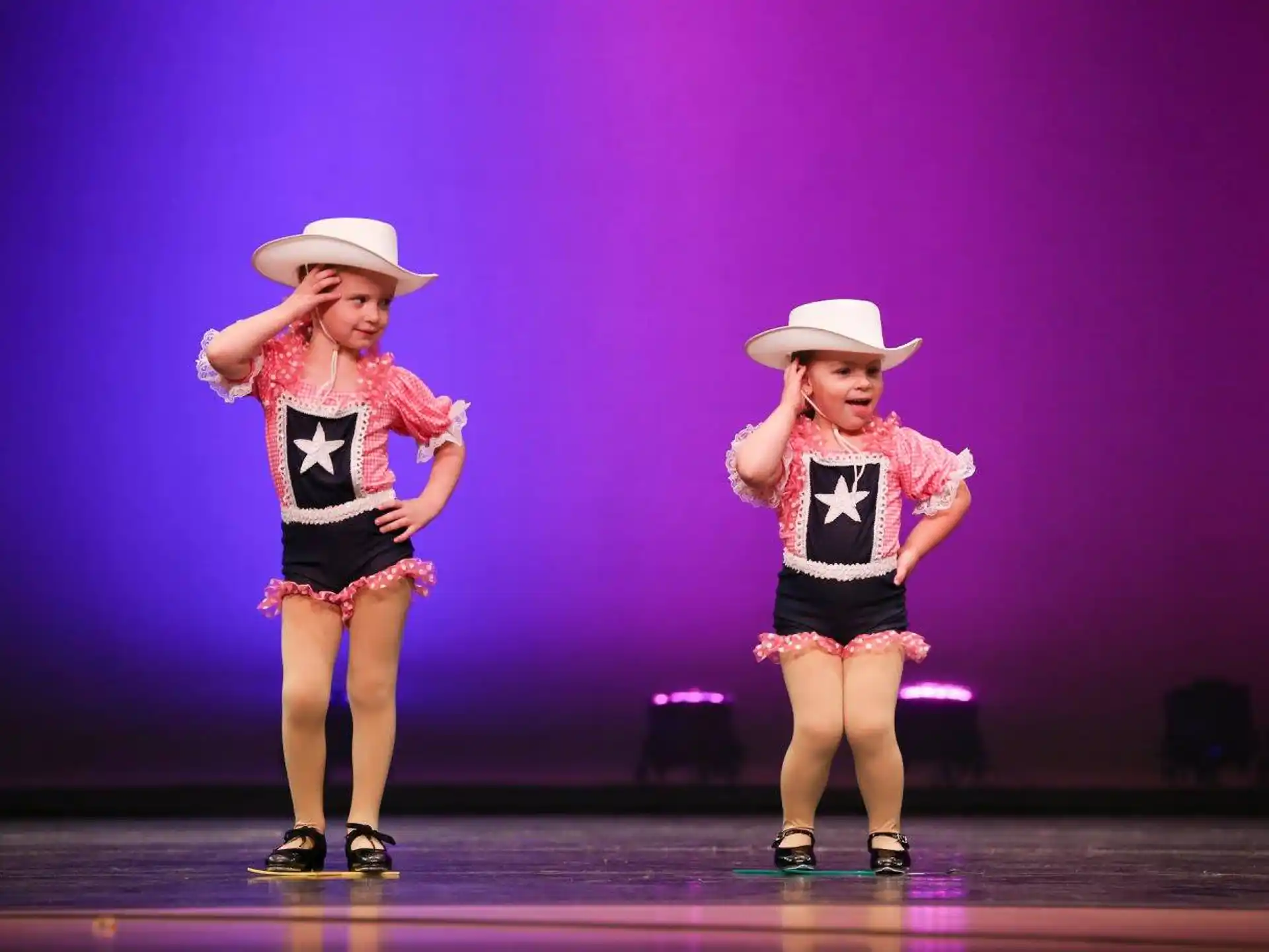 two girls wearing hats and standing on a stage