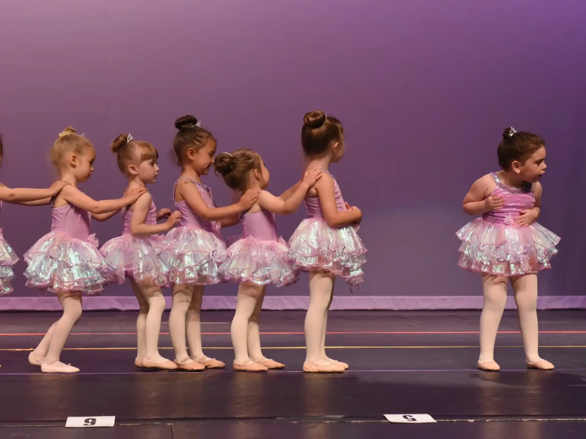 a group of girls in dresses on a stage