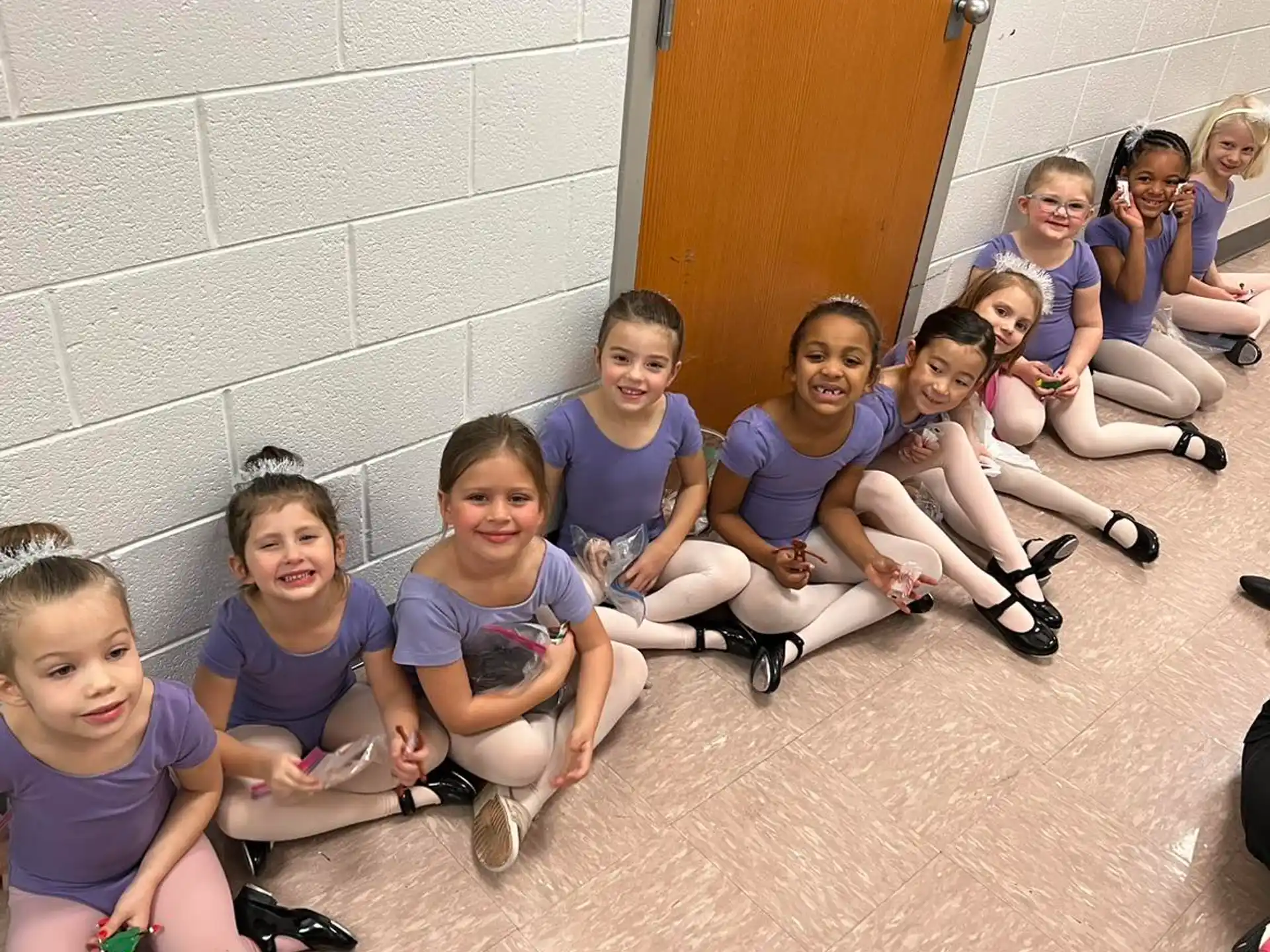 a group of children sitting on the ground posing for the camera