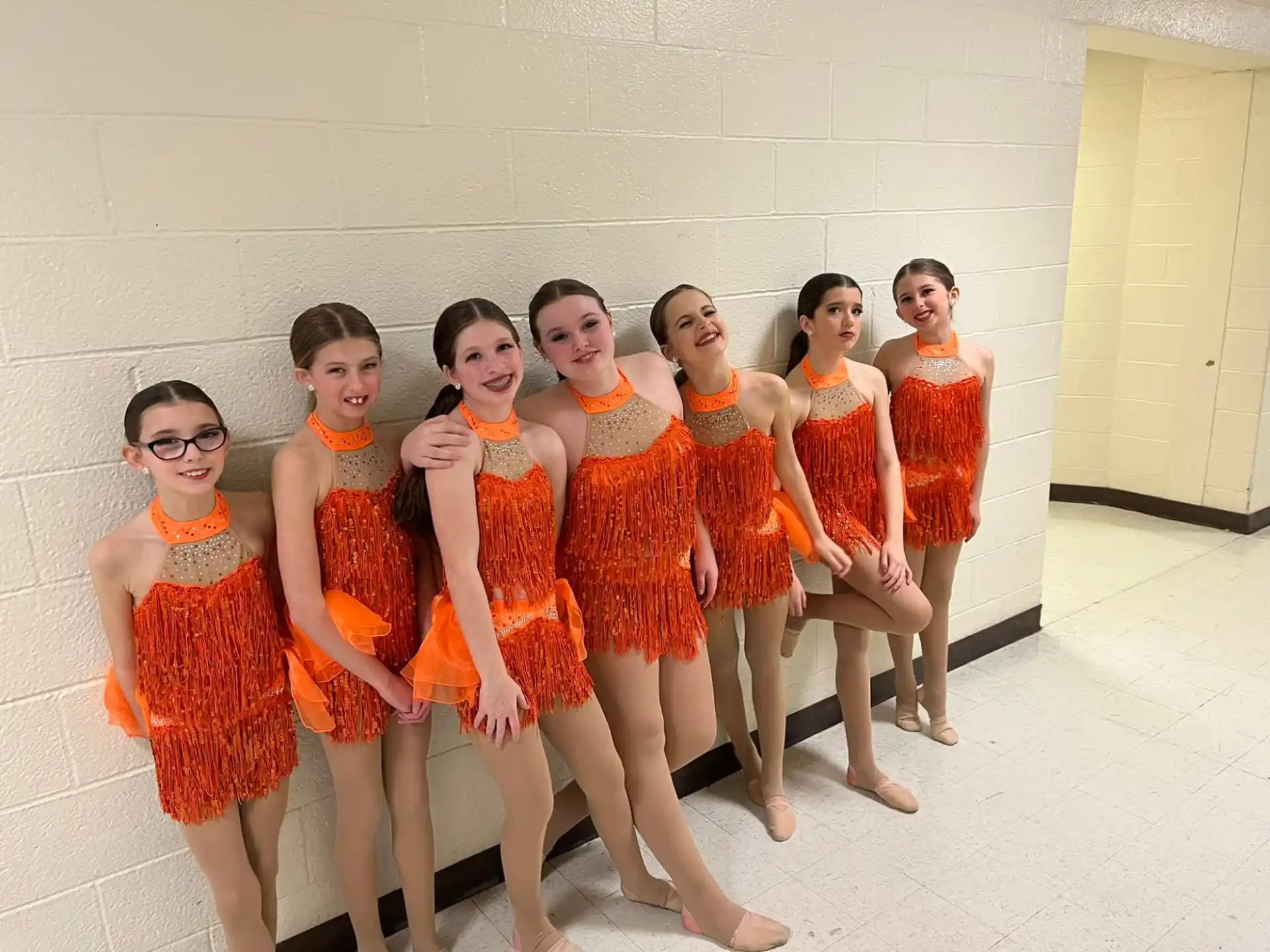 a group of women in orange dresses