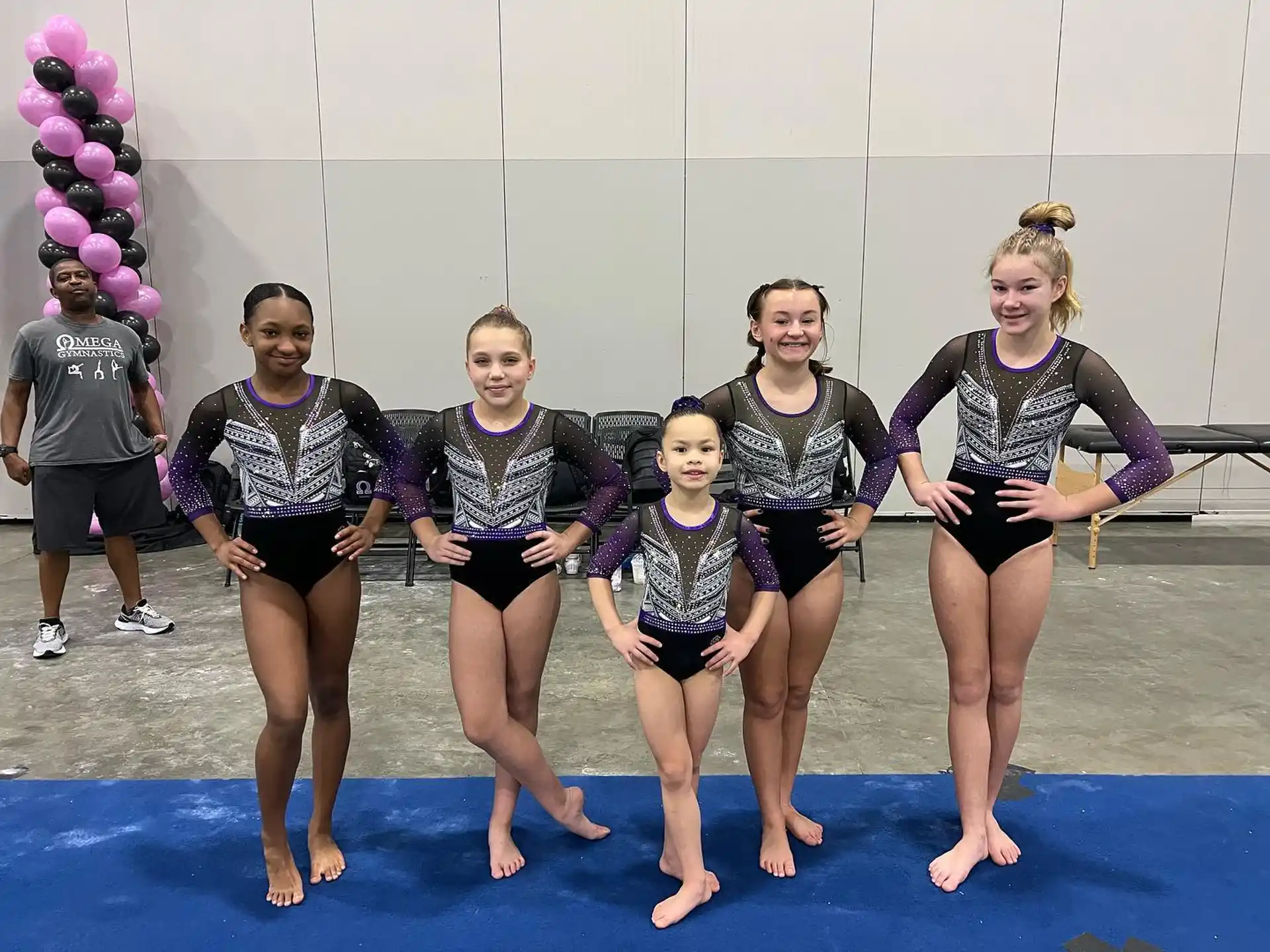 a group of girls wearing swimsuits and standing on a blue mat
