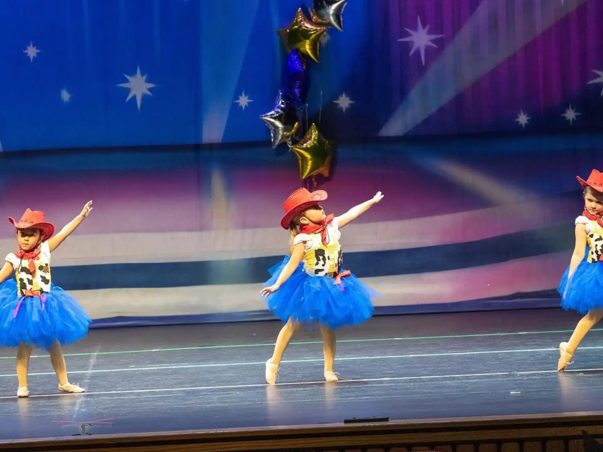 a group of girls in blue dresses and hats on a stage